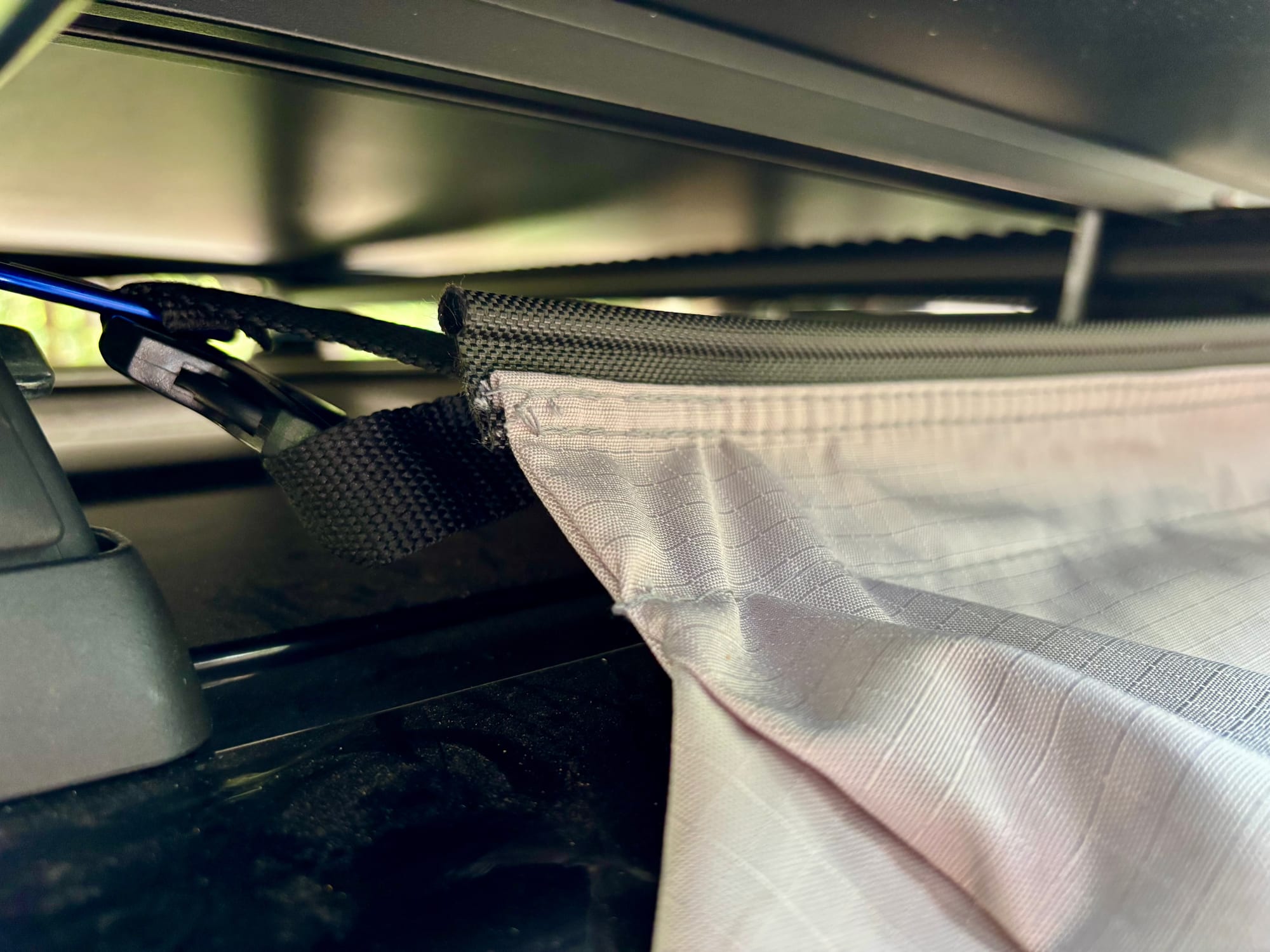 The top edge of the Kings storage bag slid into the sail track on a rooftop tent, with a quick-release clip beside it