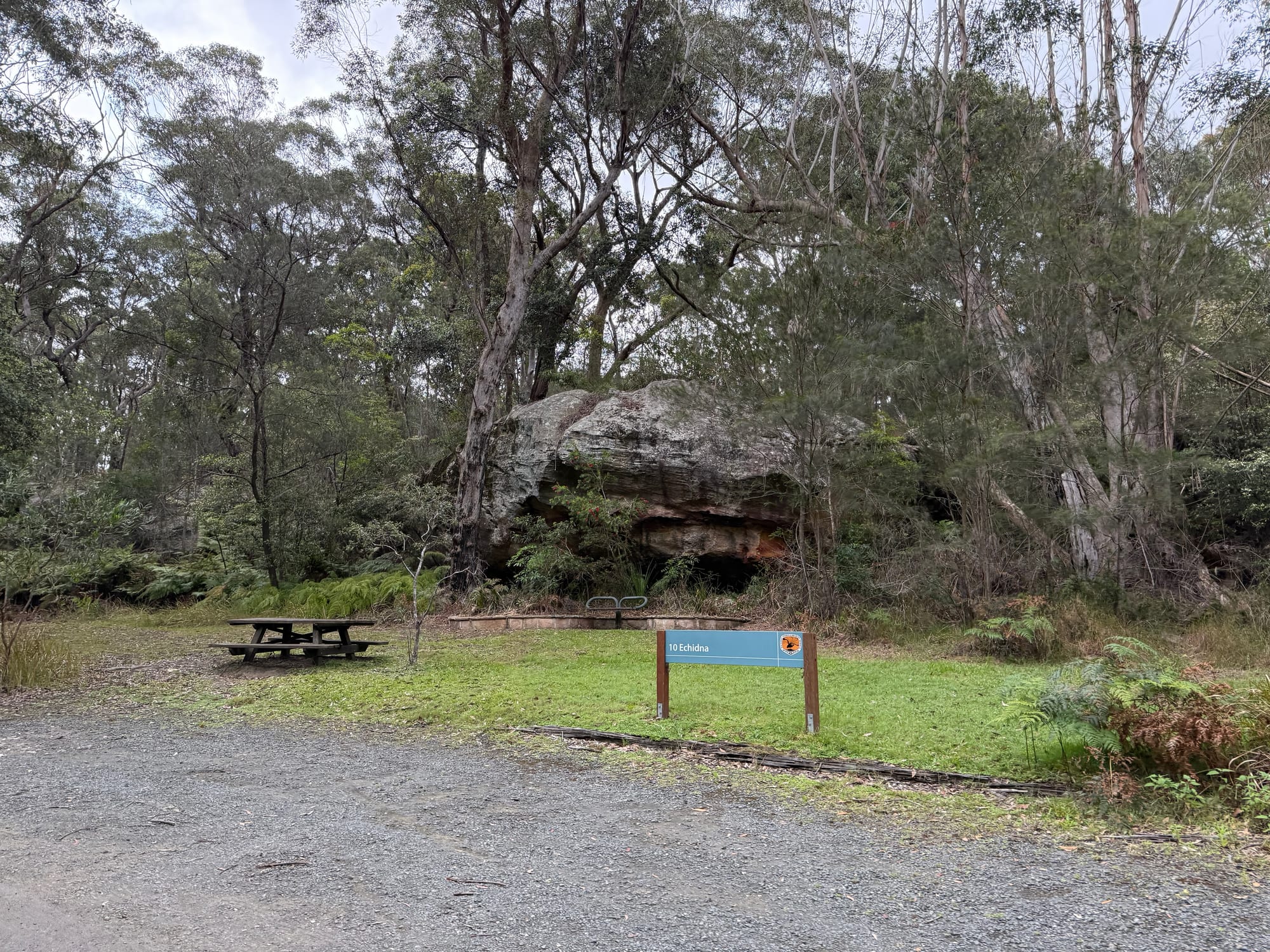 A picnic table on the lawn at Commandment Rock picnic area, with large sandstone boulders behind