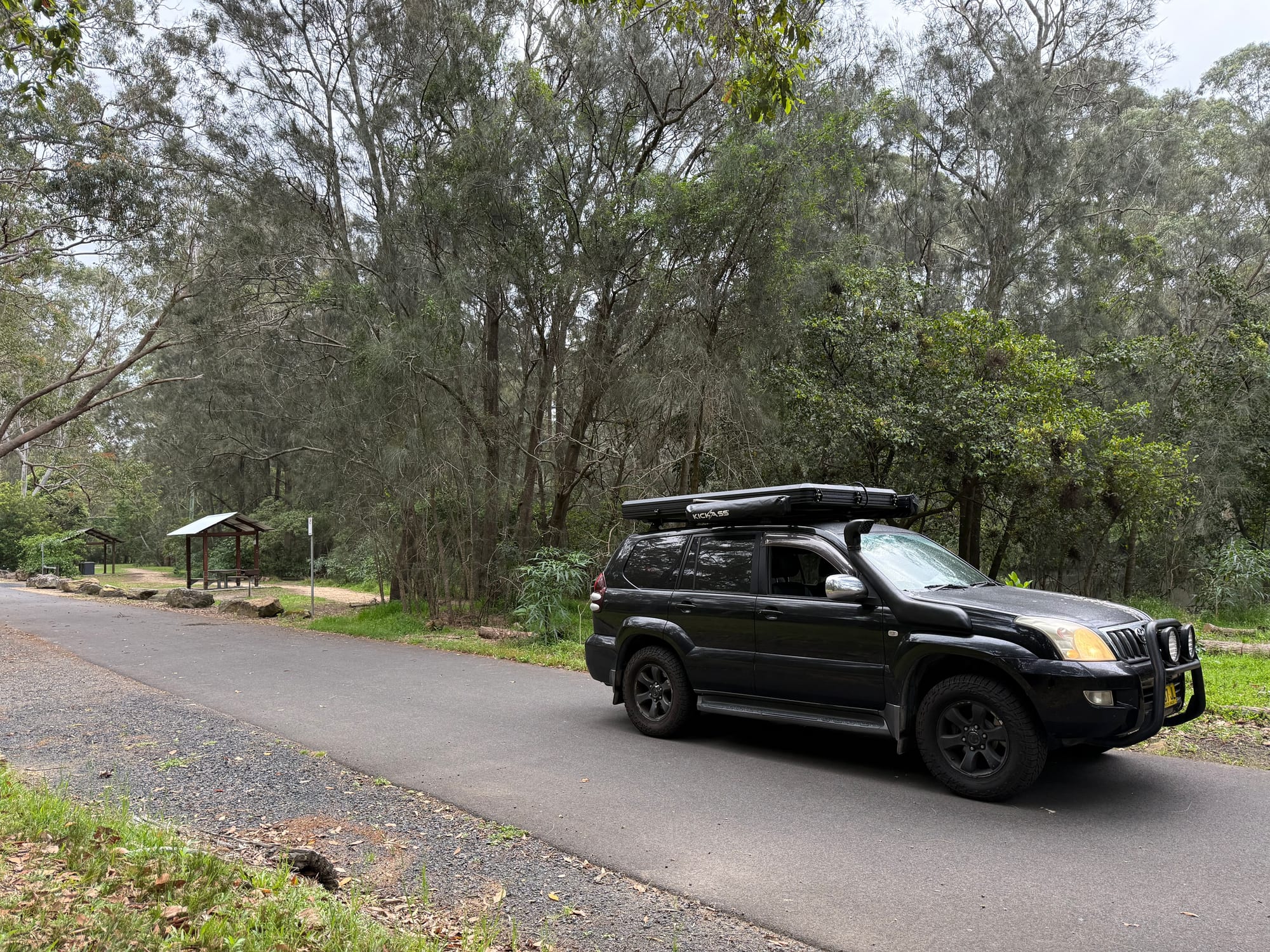 Our black Prado parked beside a picnic shelter on the road through Lane Cove National Park