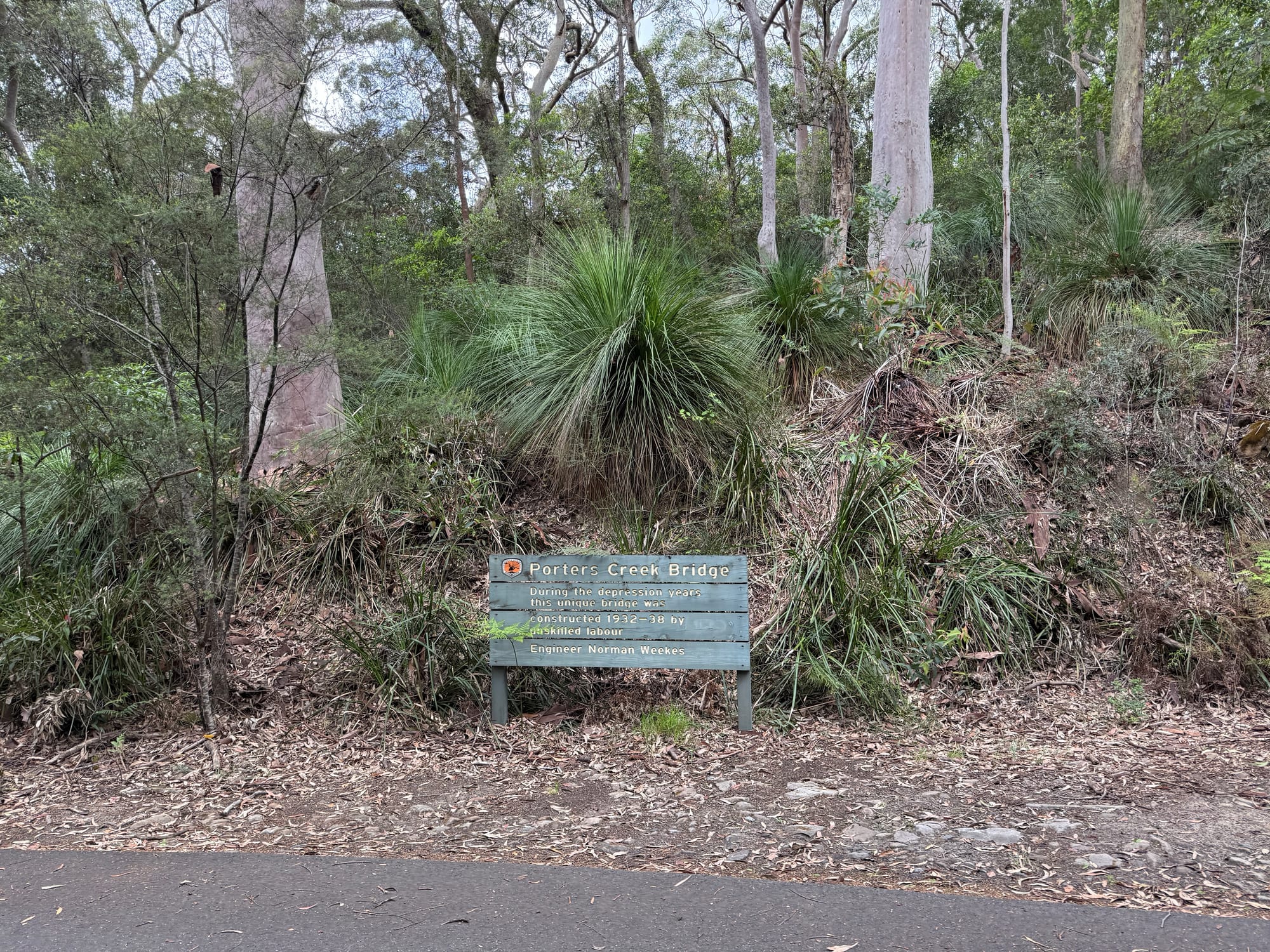The Porters Creek Bridge history sign beside a grass tree