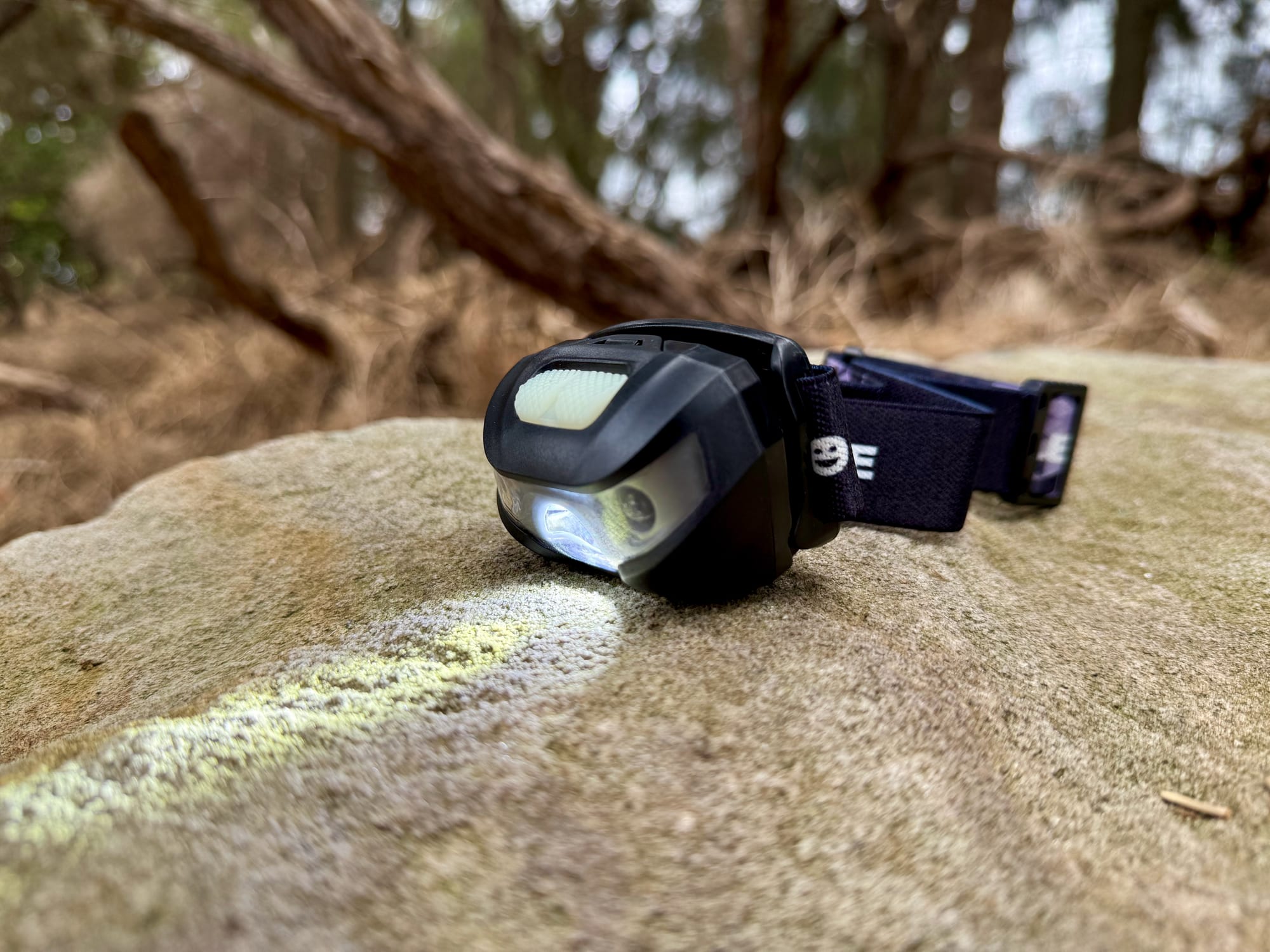 The Lepro 3200008 tilted down with its white light on, lighting the rock in front of it