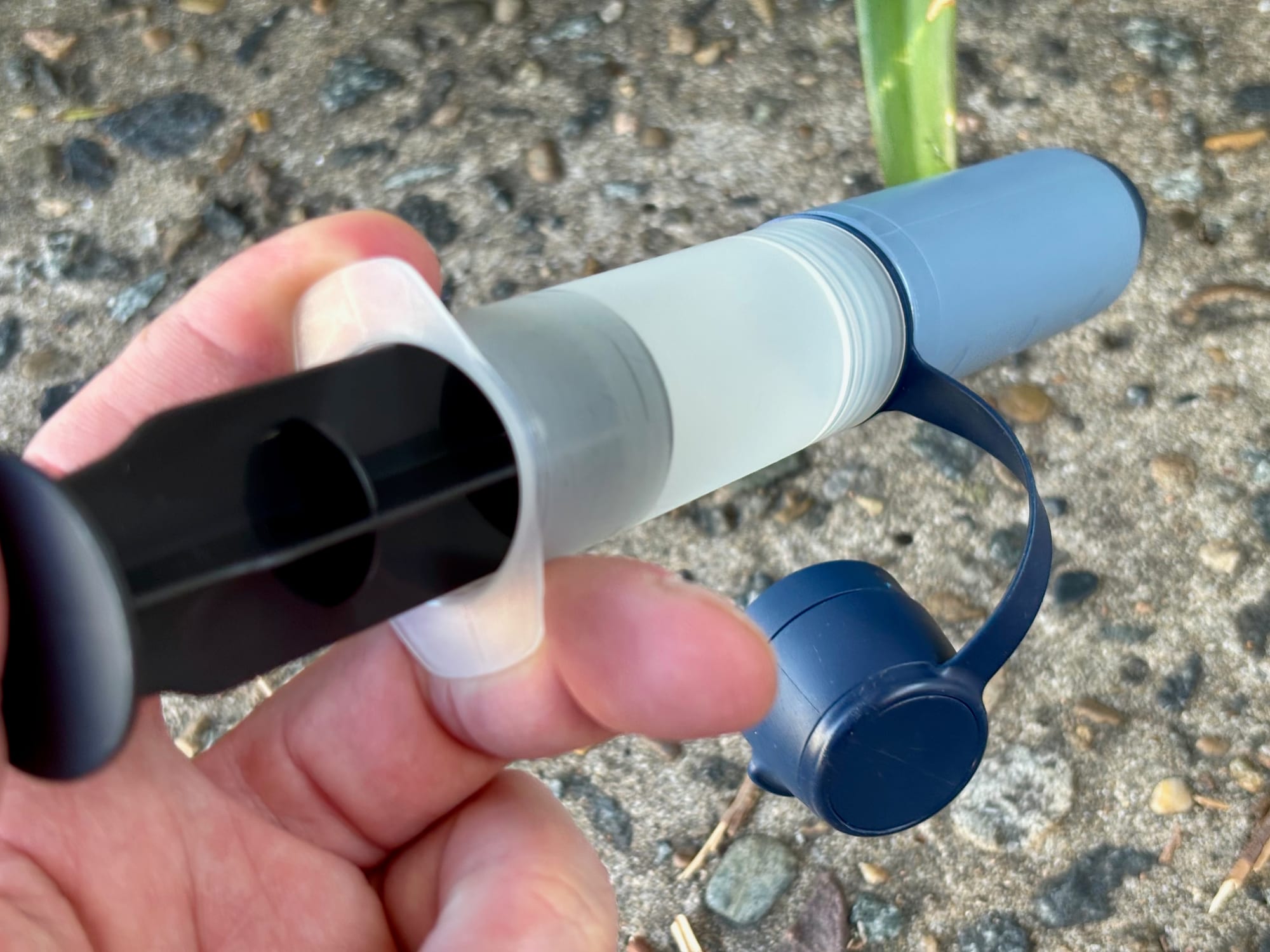 A hand pressing the backwash syringe into the Peak Solo, the cap hanging on its strap