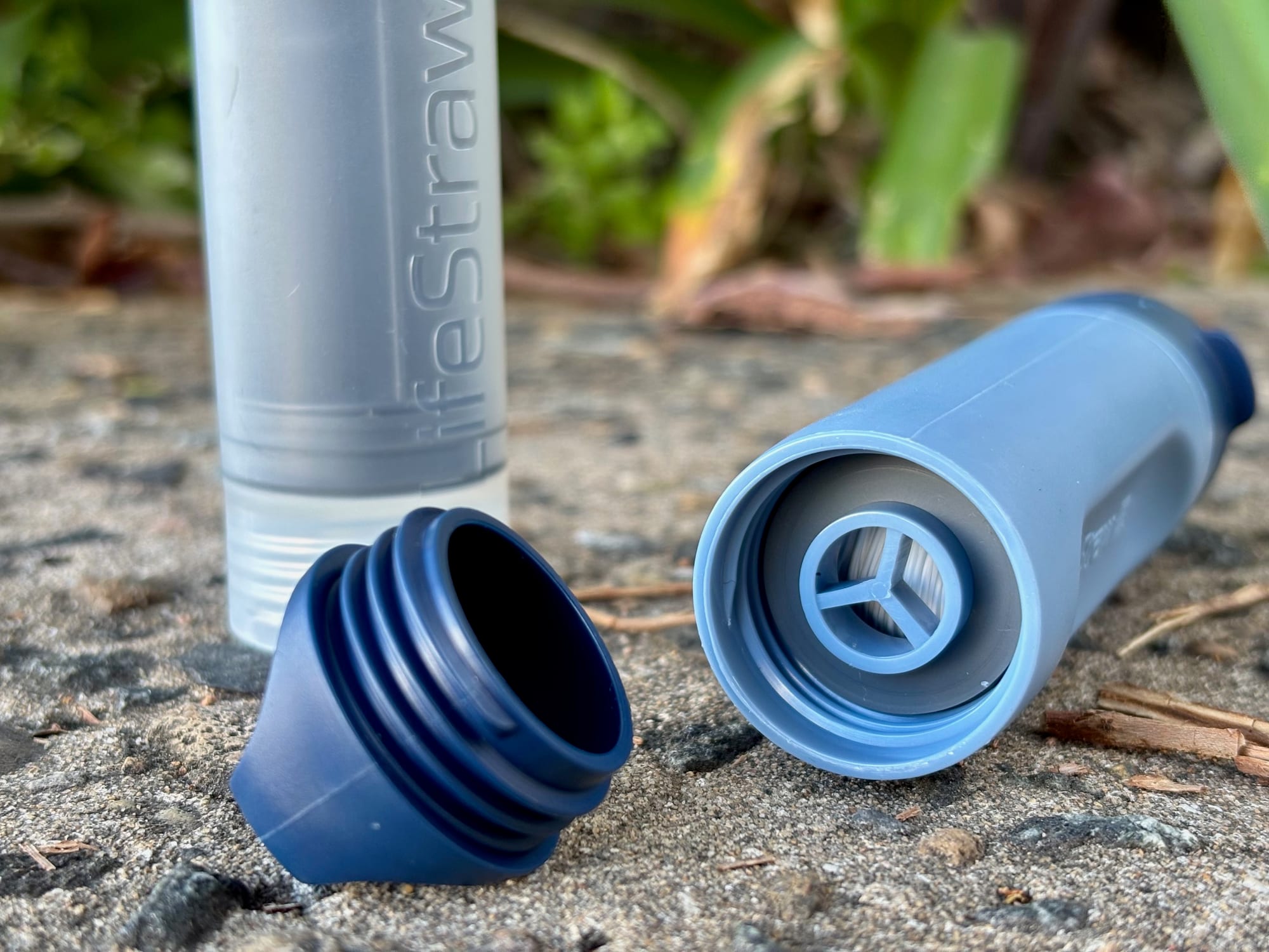 The Peak Solo with its bottom cap off, showing the filter inside, next to the cap and the syringe