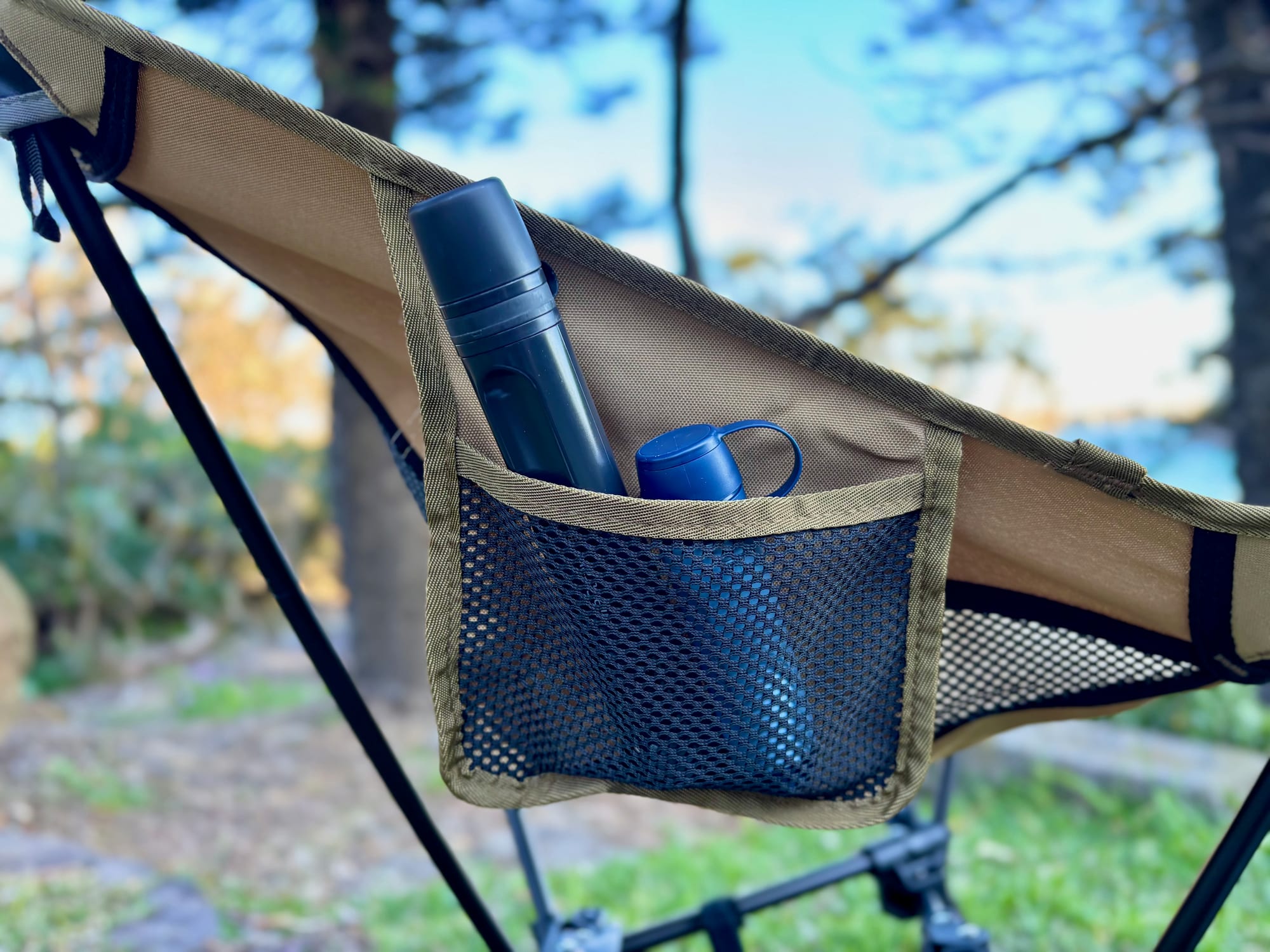 The LifeStraw Peak Solo in the mesh side pocket of a camp chair, with the sea behind