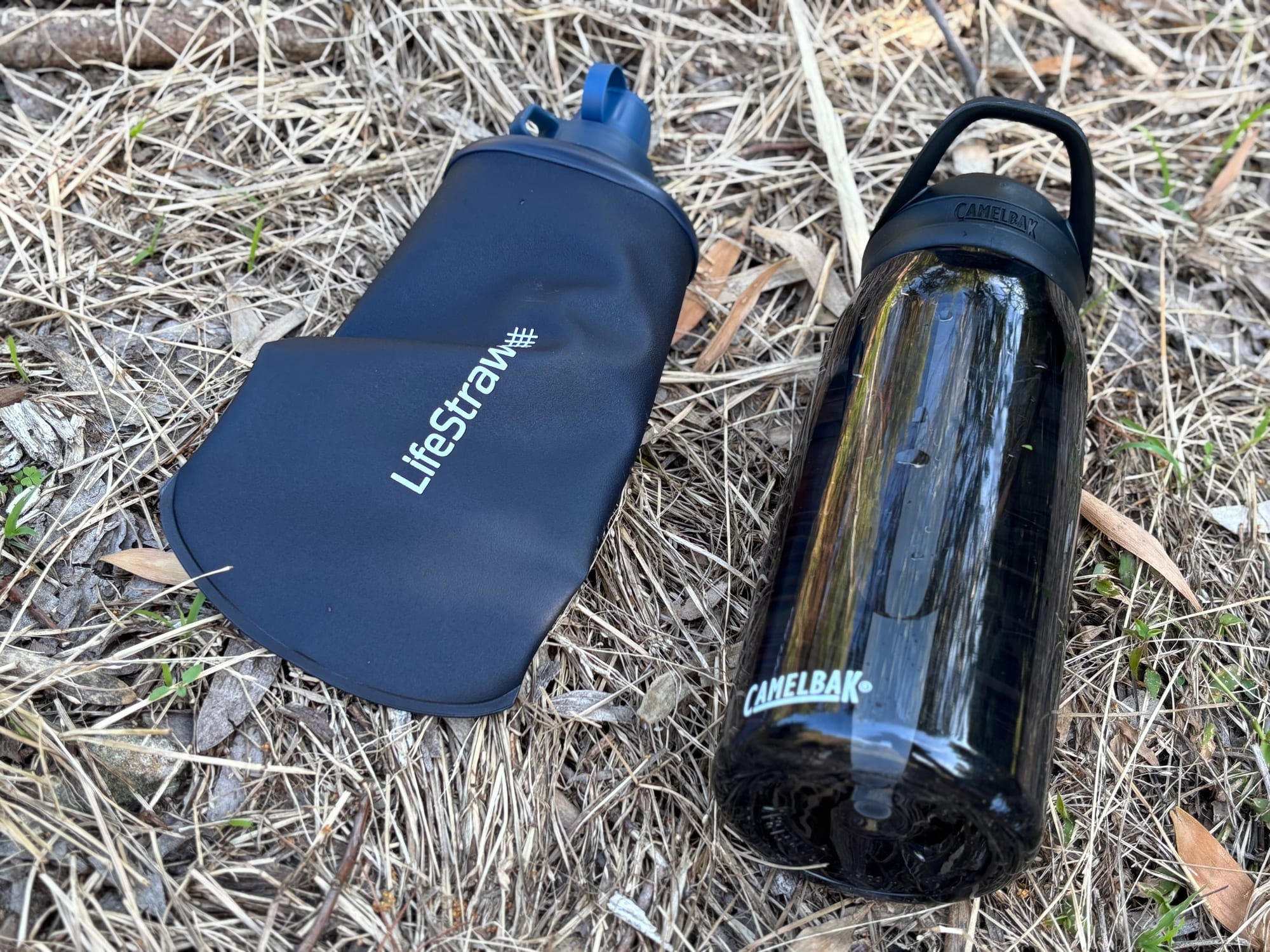 The empty LifeStraw Peak Squeeze lying flat next to a rigid CamelBak bottle