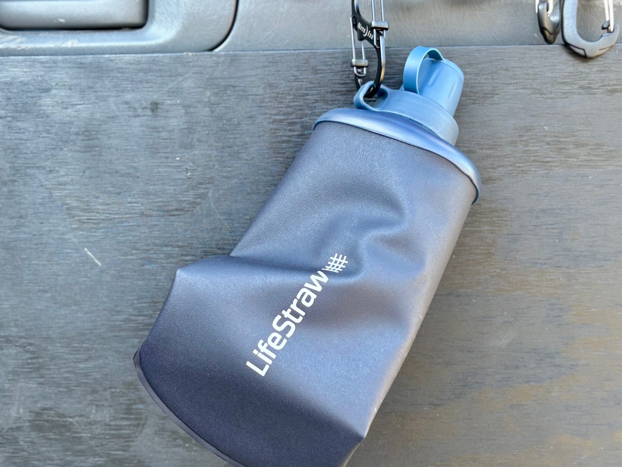 The LifeStraw Peak Squeeze hanging from a carabiner on the 4WD
