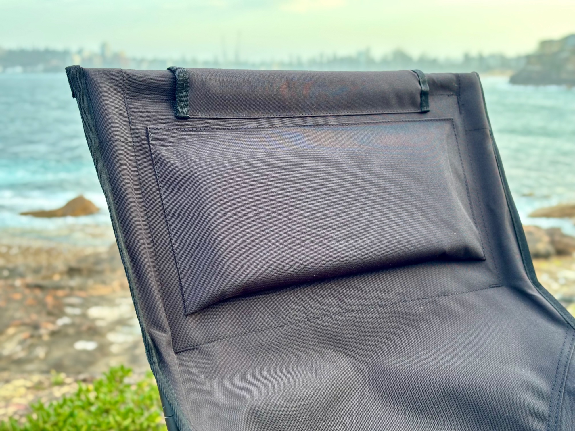 The headrest pillow at the top of the Moon Lence high back chair, with the sea behind