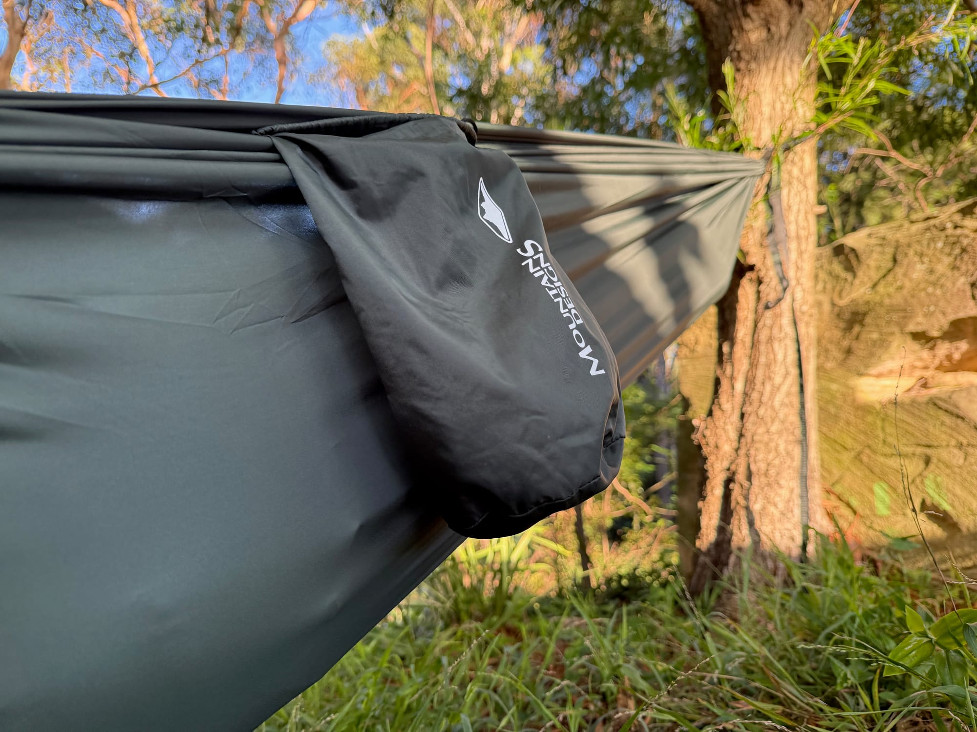 The Mountain Designs stuff sack hanging from the side of the hammock, with trees and sandstone behind