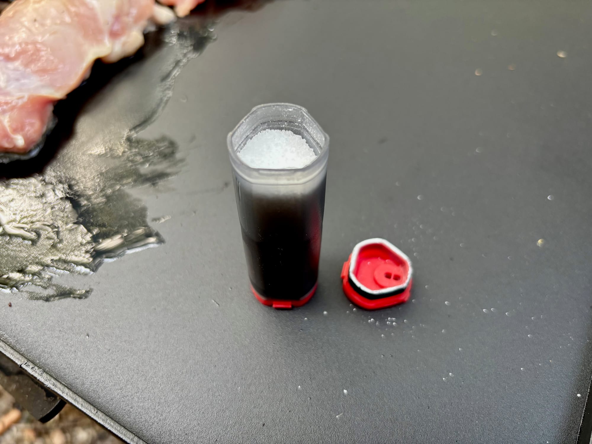 The MSR shaker with one end cap unscrewed and salt inside, on a camp hotplate