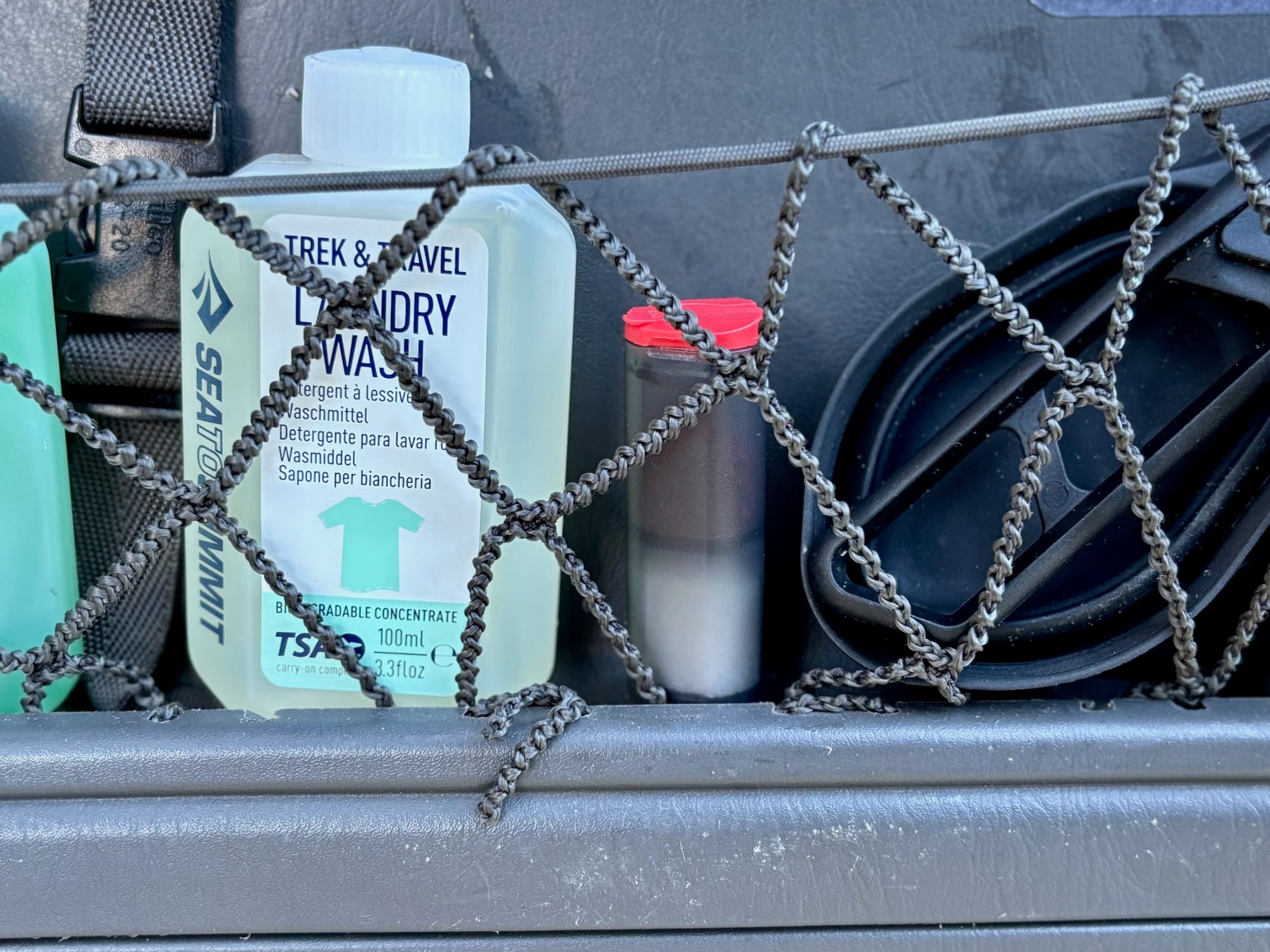 The MSR shaker tucked into a mesh storage net next to a bottle of laundry wash