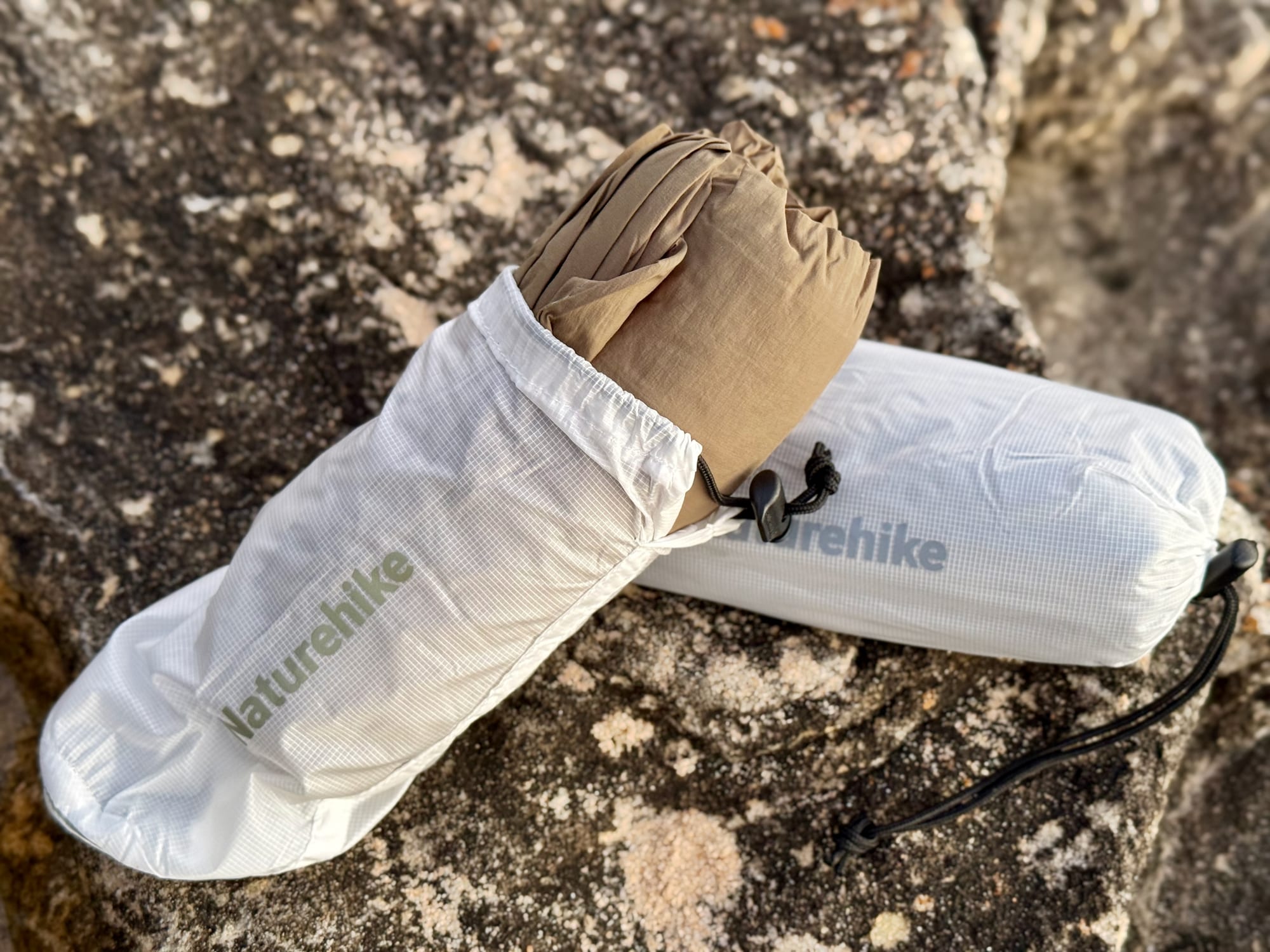 A Naturehike sleeping bag liner being pulled out of its white stuff sack