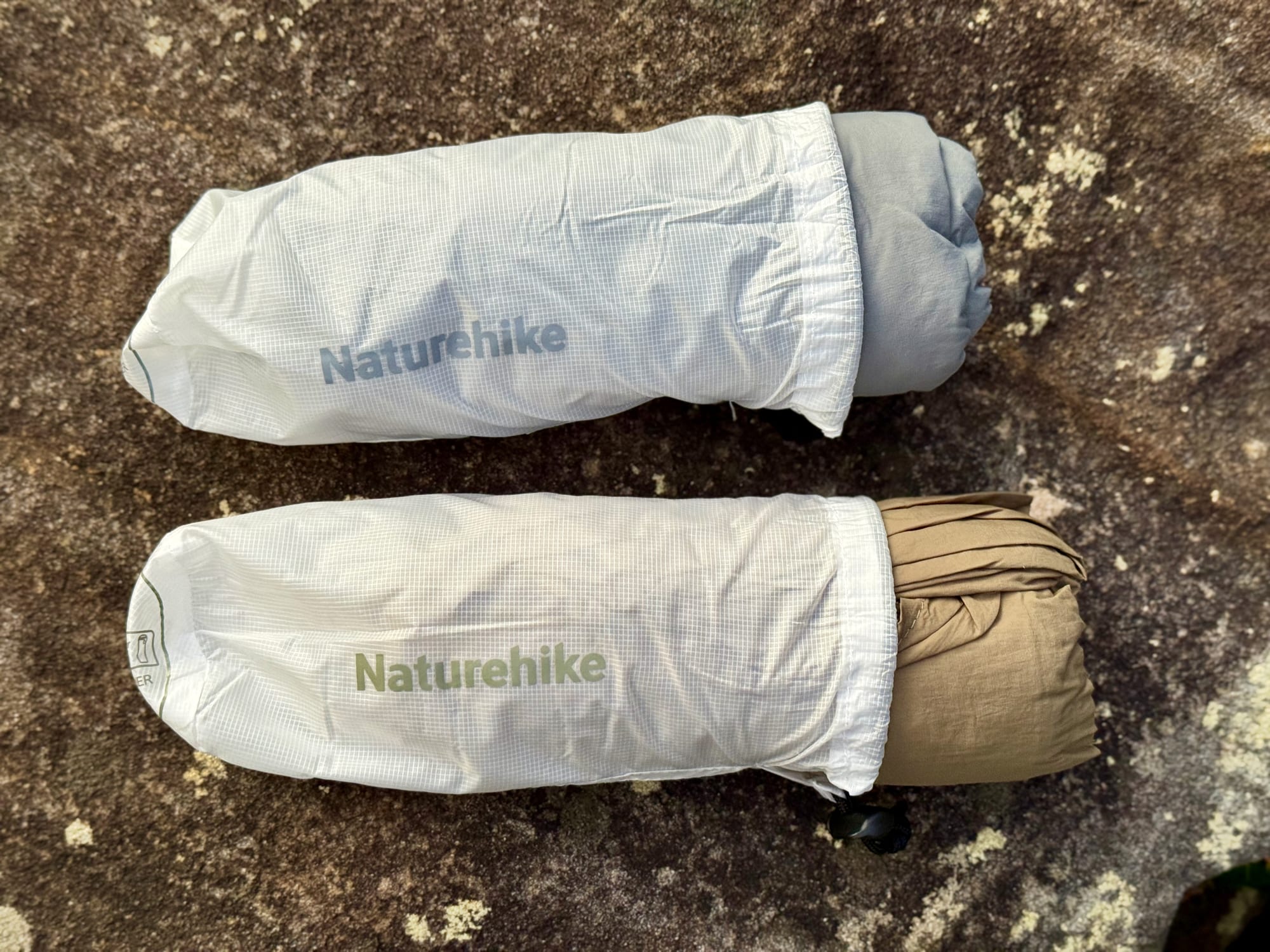 A grey and a brown Naturehike sleeping bag liner, each half out of its stuff sack