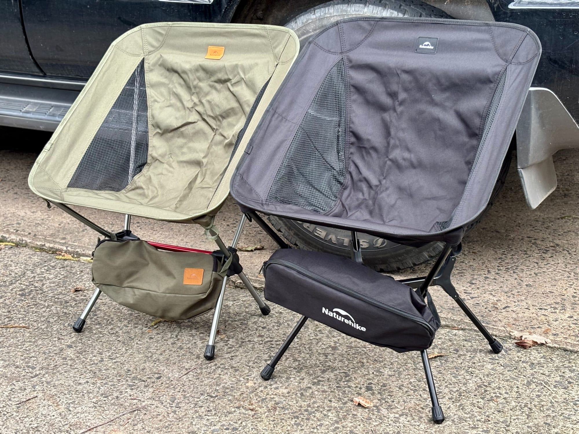 The black Naturehike YL01 next to the khaki YL08, each with its carry bag under the seat