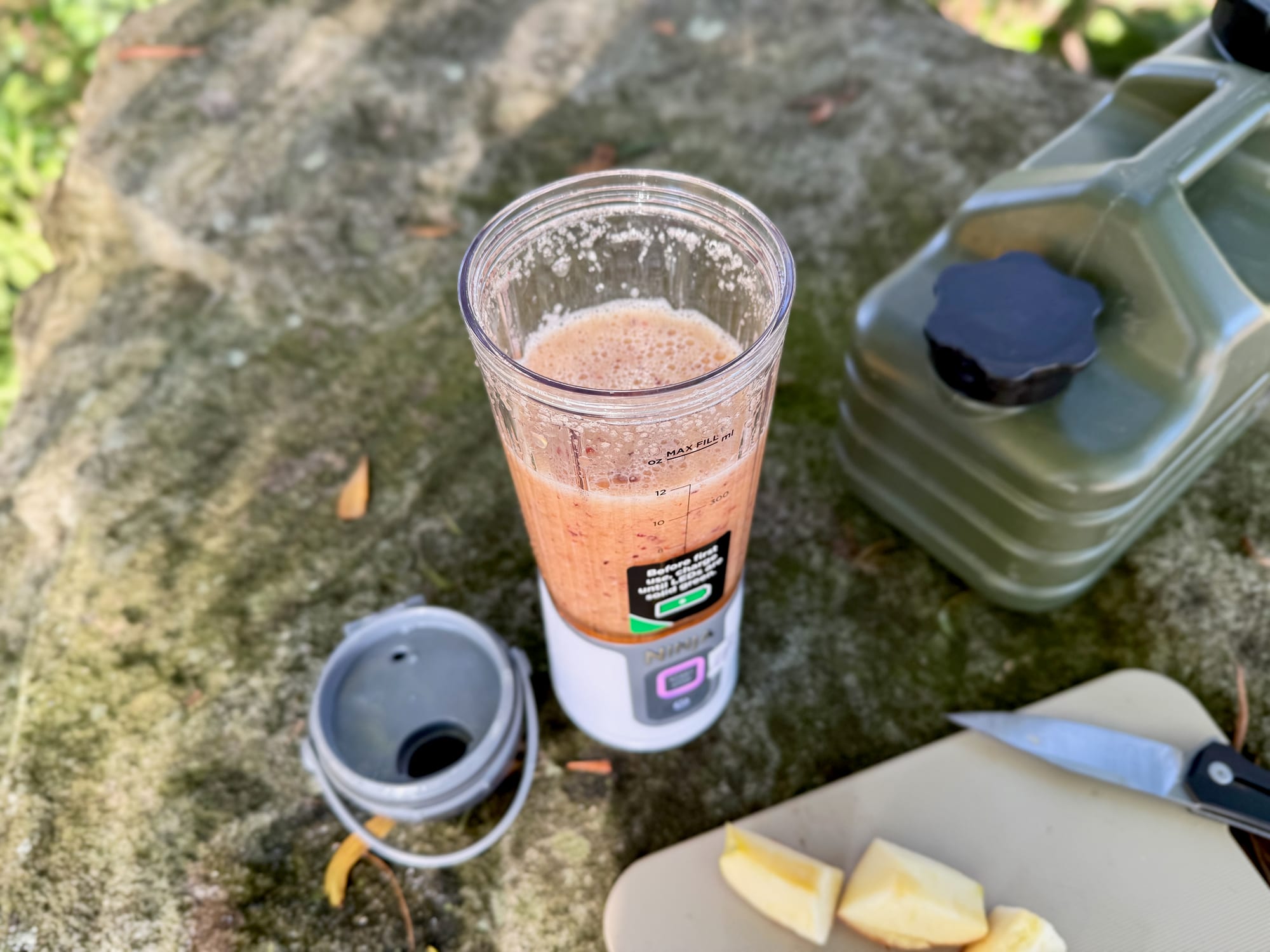 The blended apple and plum smoothie in the Ninja Blast jar, seen from above, next to the sip lid