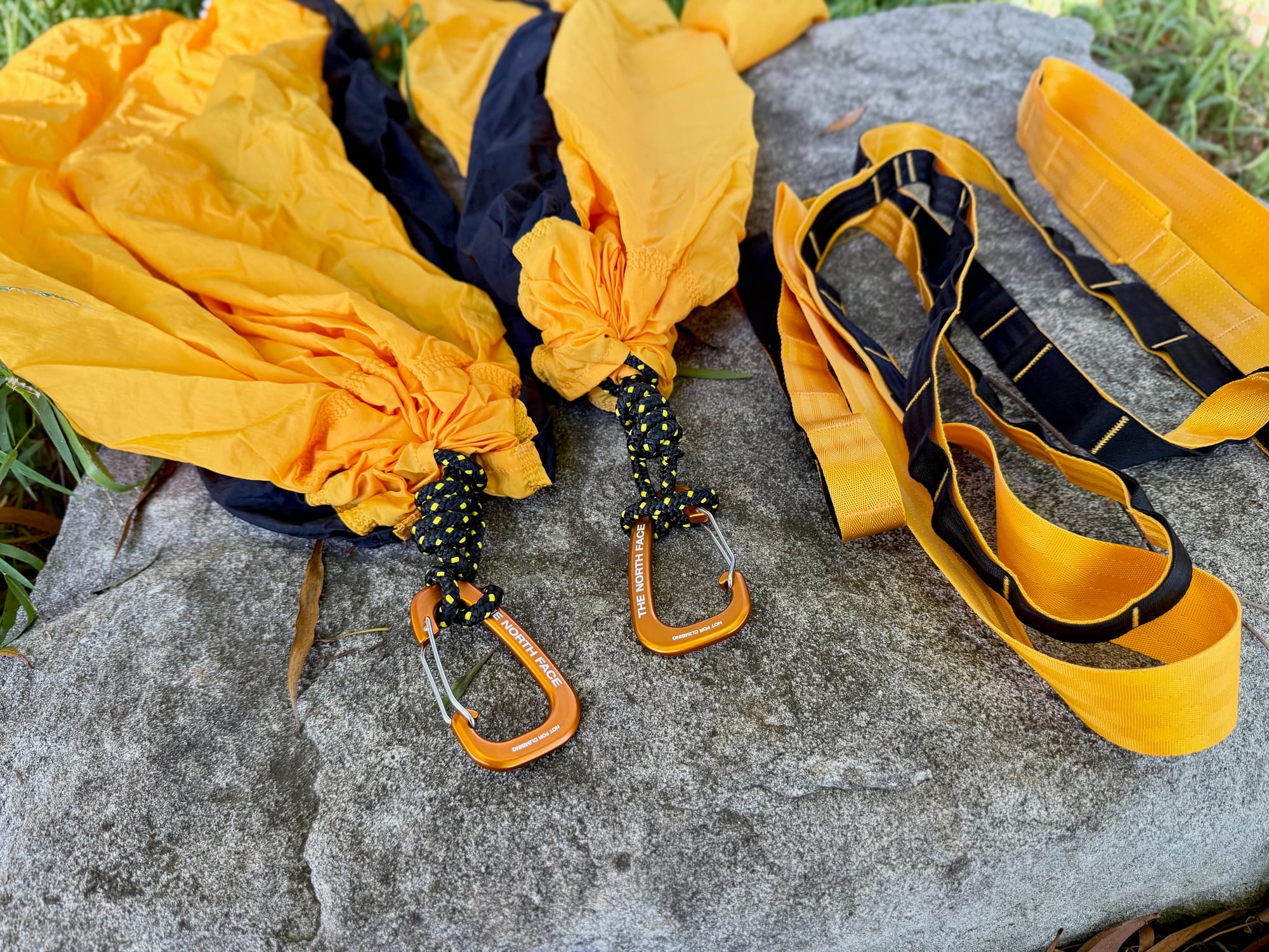 The two orange carabiners on knotted cord at the hammock ends, next to the webbing tree straps