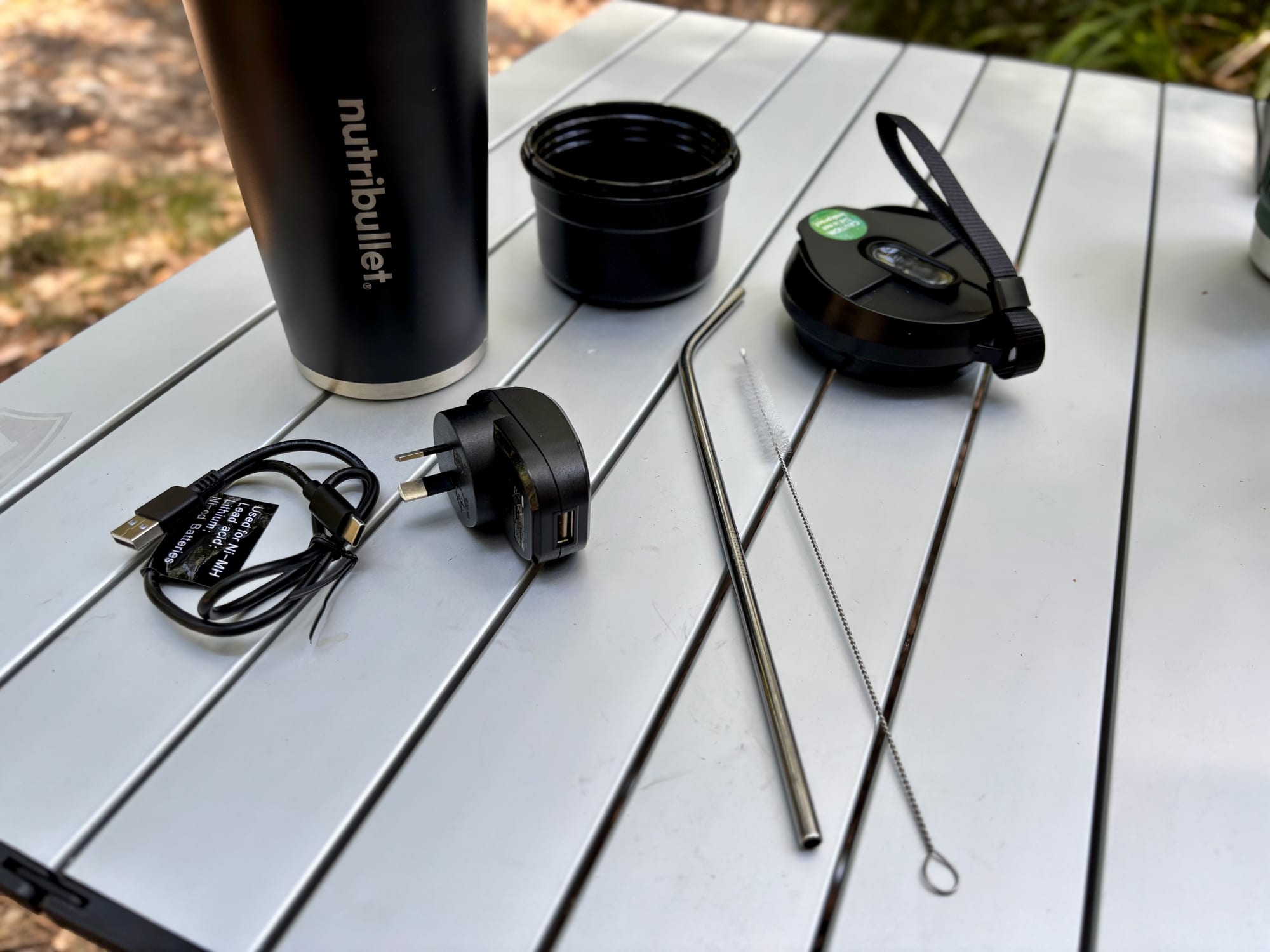 The NutriBullet Flip with its to-go lid, straw, cleaning brush, charging cable and charging block
