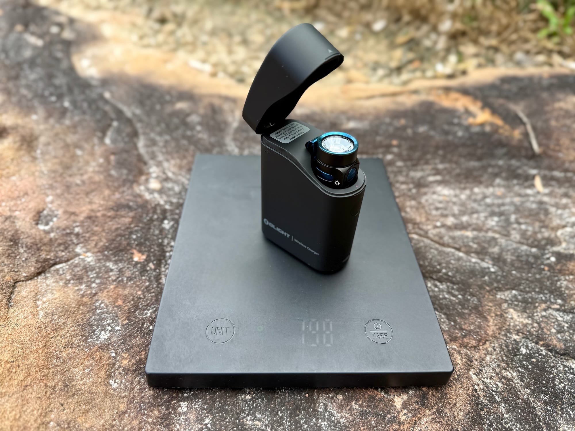 The Baton 4 in its open charging case on a kitchen scale showing 198 g