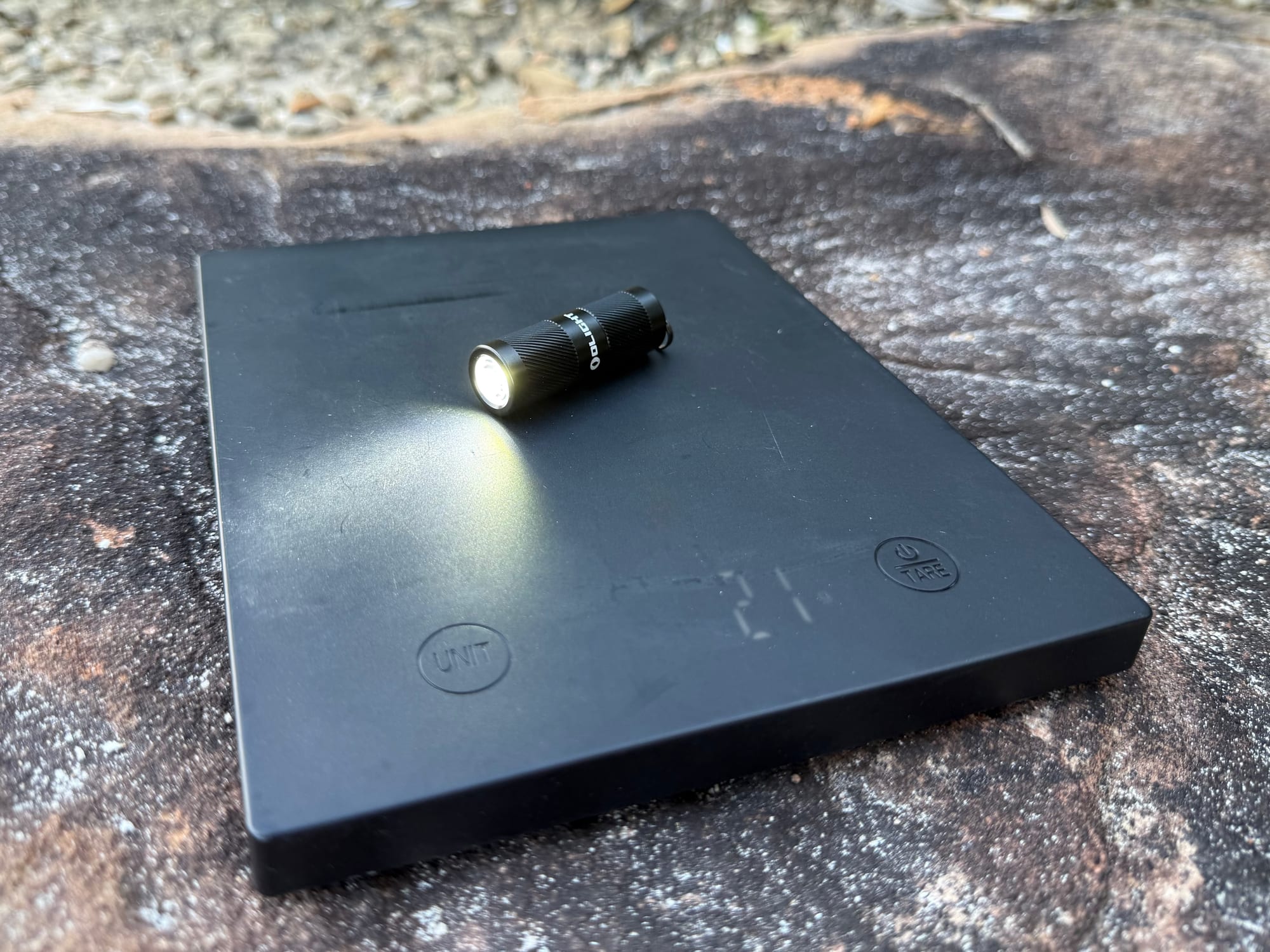 The Olight i1R 2 Pro switched on, on a digital scale showing 21 grams