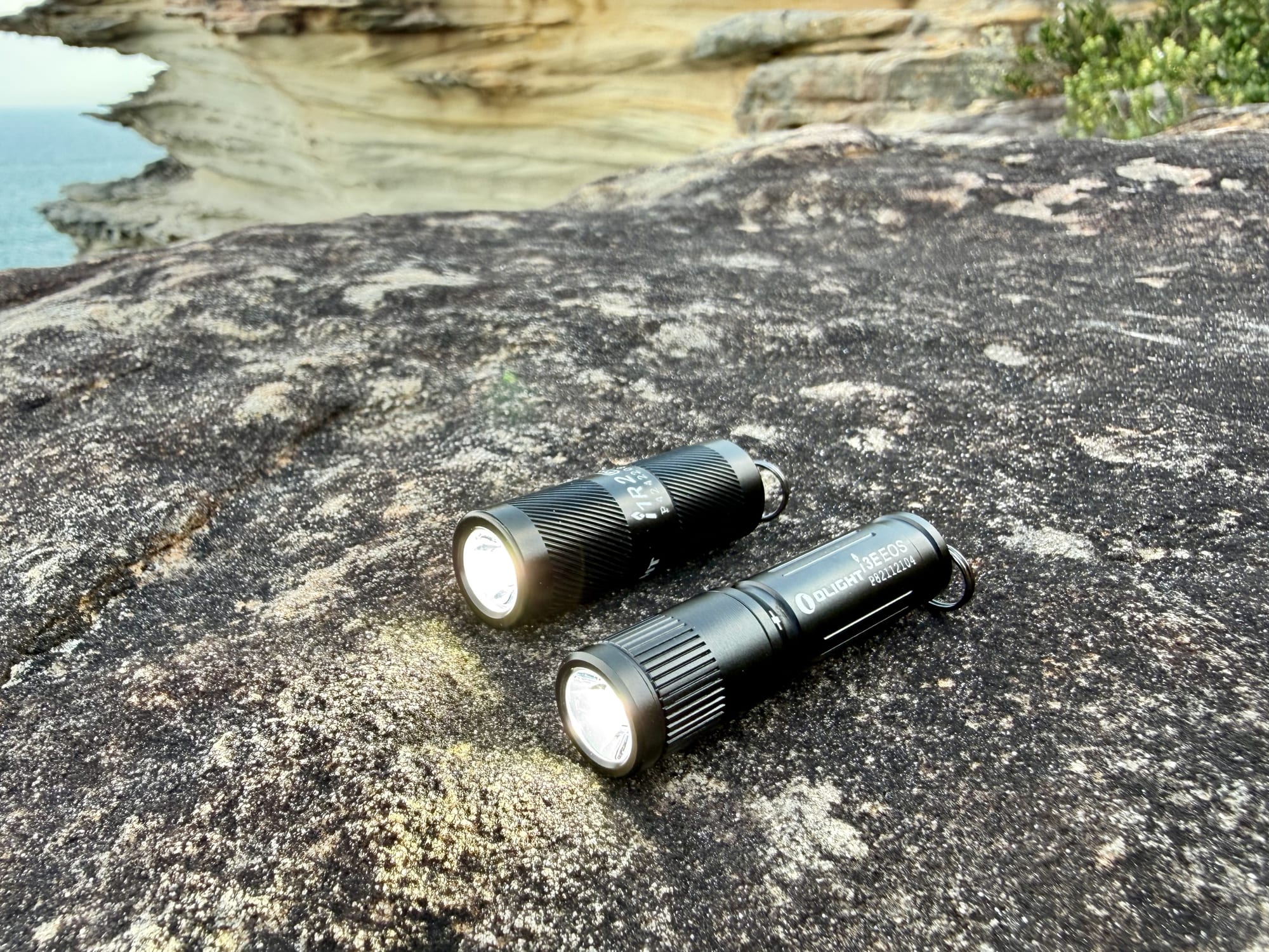 The Olight i1R 2 Pro and i3E EOS side by side, both switched on