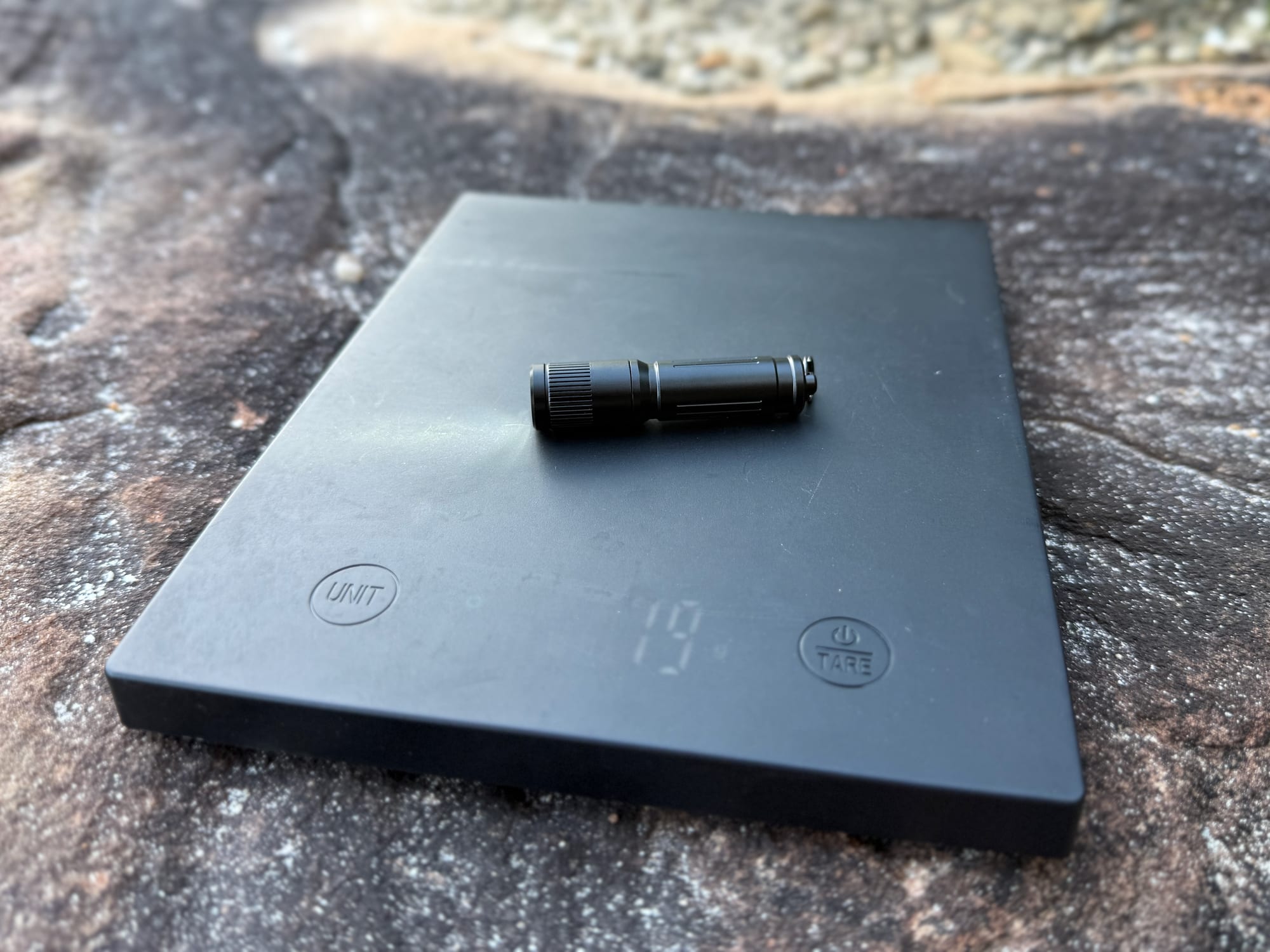 The Olight i3E EOS on a digital scale showing 19 grams
