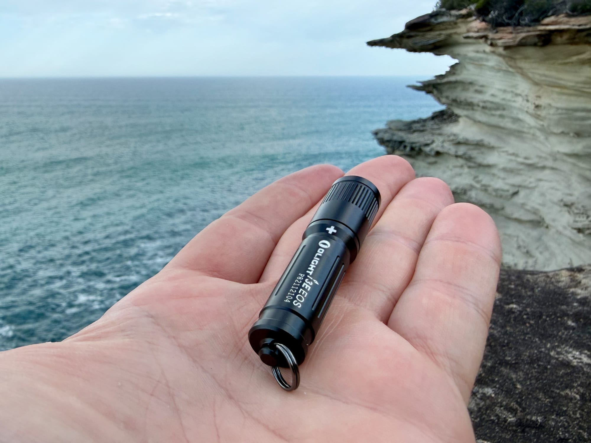 The Olight i3E EOS lying in an open hand