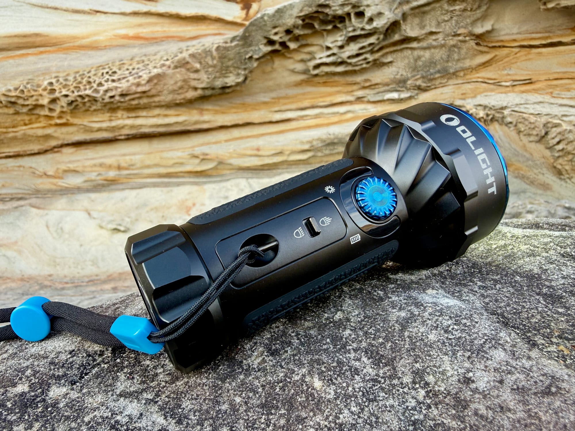 The Olight Marauder Mini with its flood and spot switched on, lying on a sandstone rock