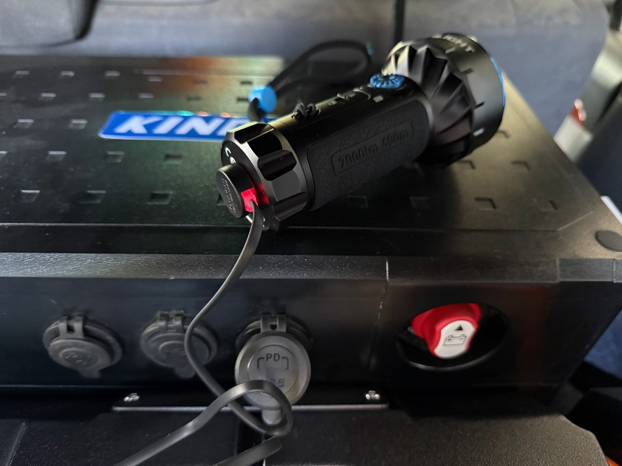 The Olight Marauder Mini charging on its magnetic cable from the 12V panel in the back of a 4WD