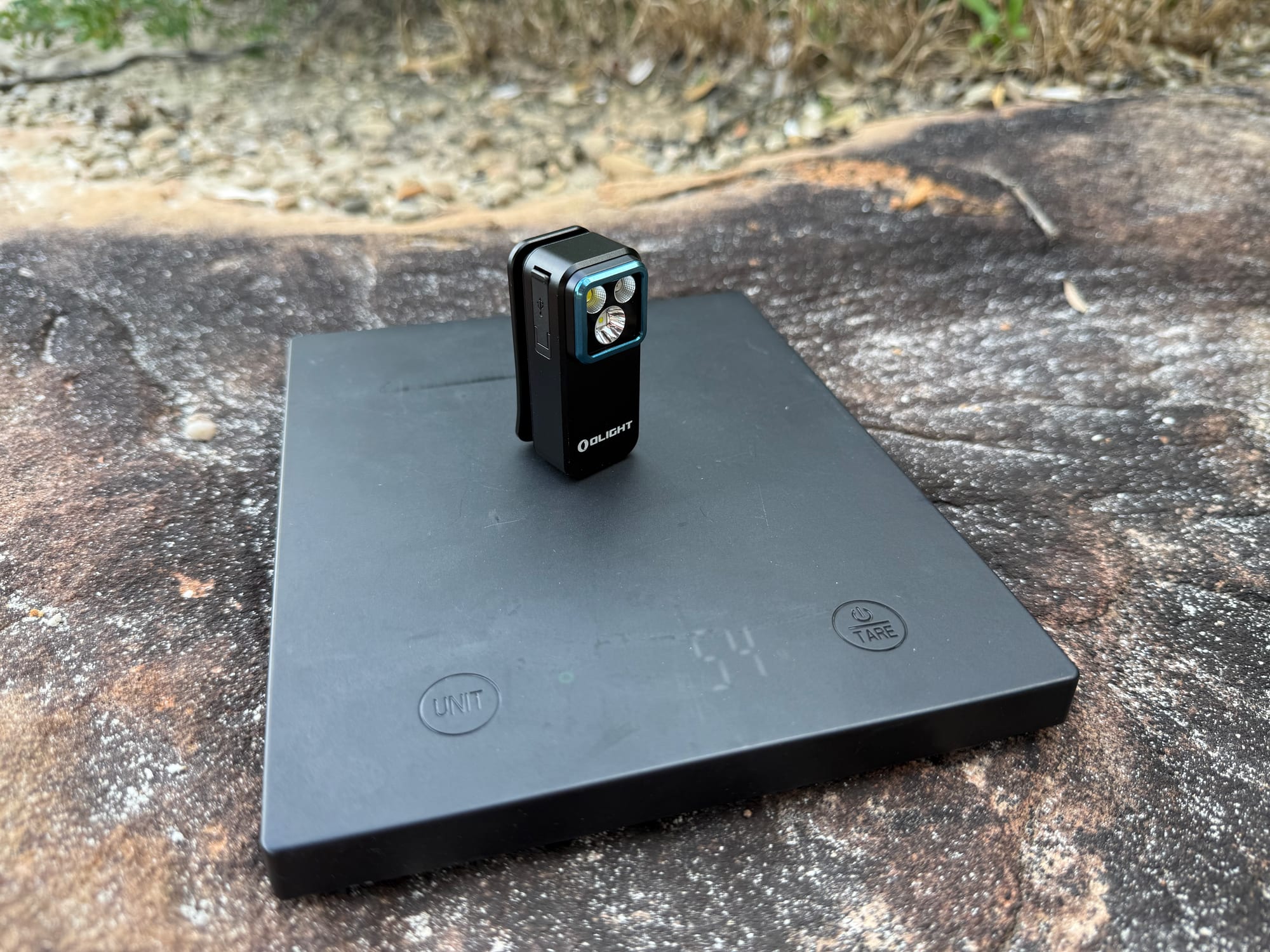 The Olight Oclip Pro on a scale showing 54 g