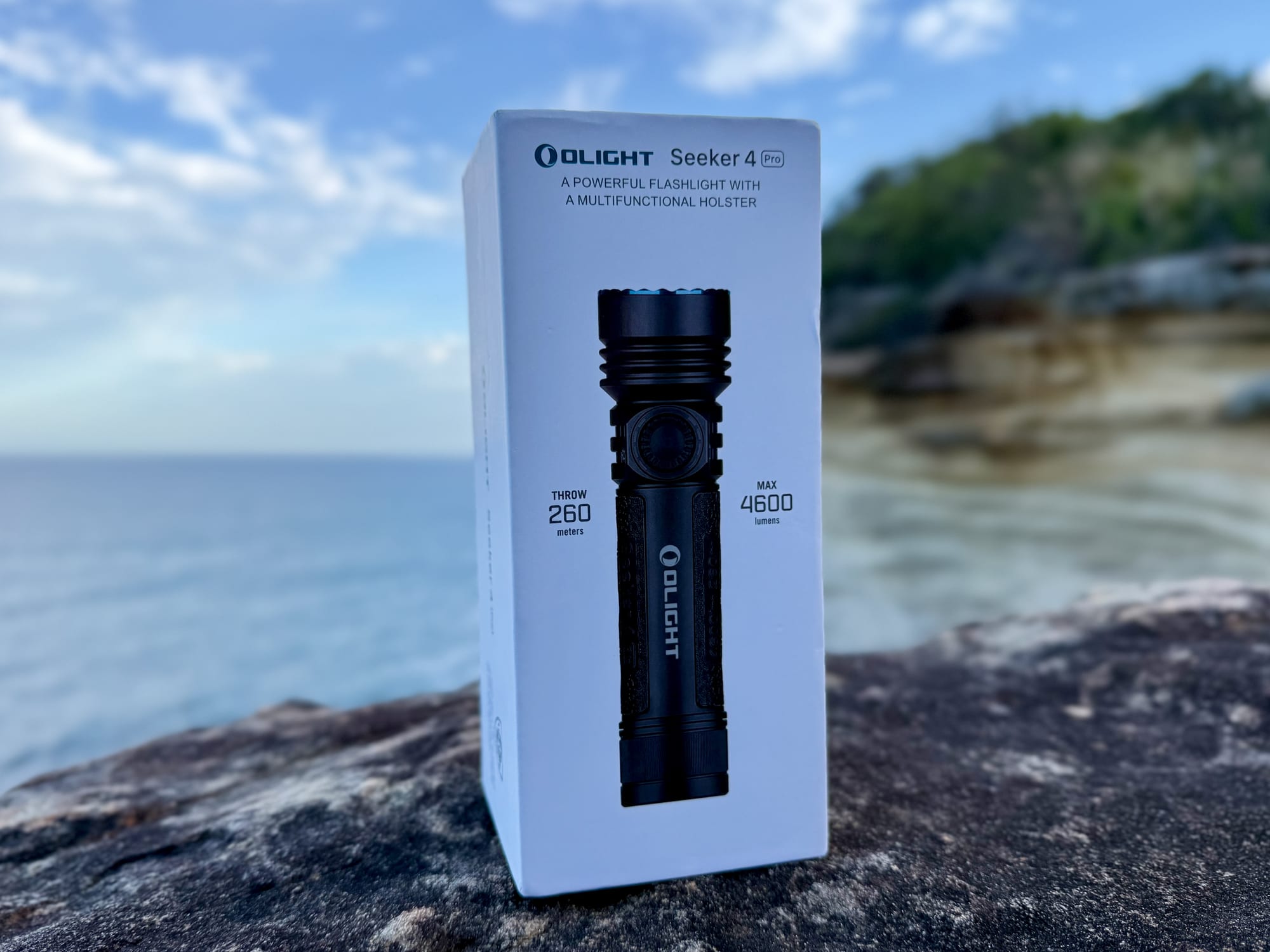 The Olight Seeker 4 Pro box on a rock by the sea: max 4,600 lumens, throw 260 m