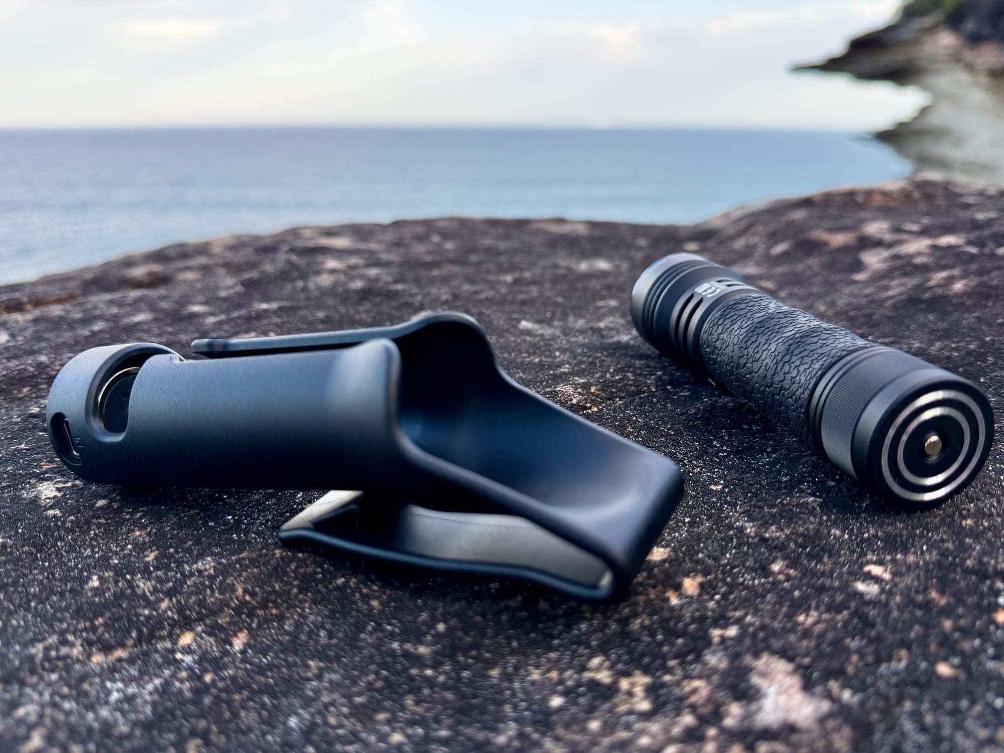 The Seeker 4 Pro holster and the tail of the torch side by side on a rock