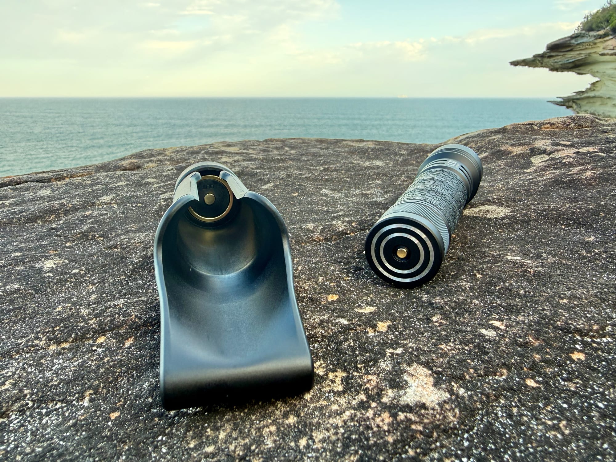The empty Seeker 4 Pro holster with the charging contacts in the bottom, next to the tail of the torch