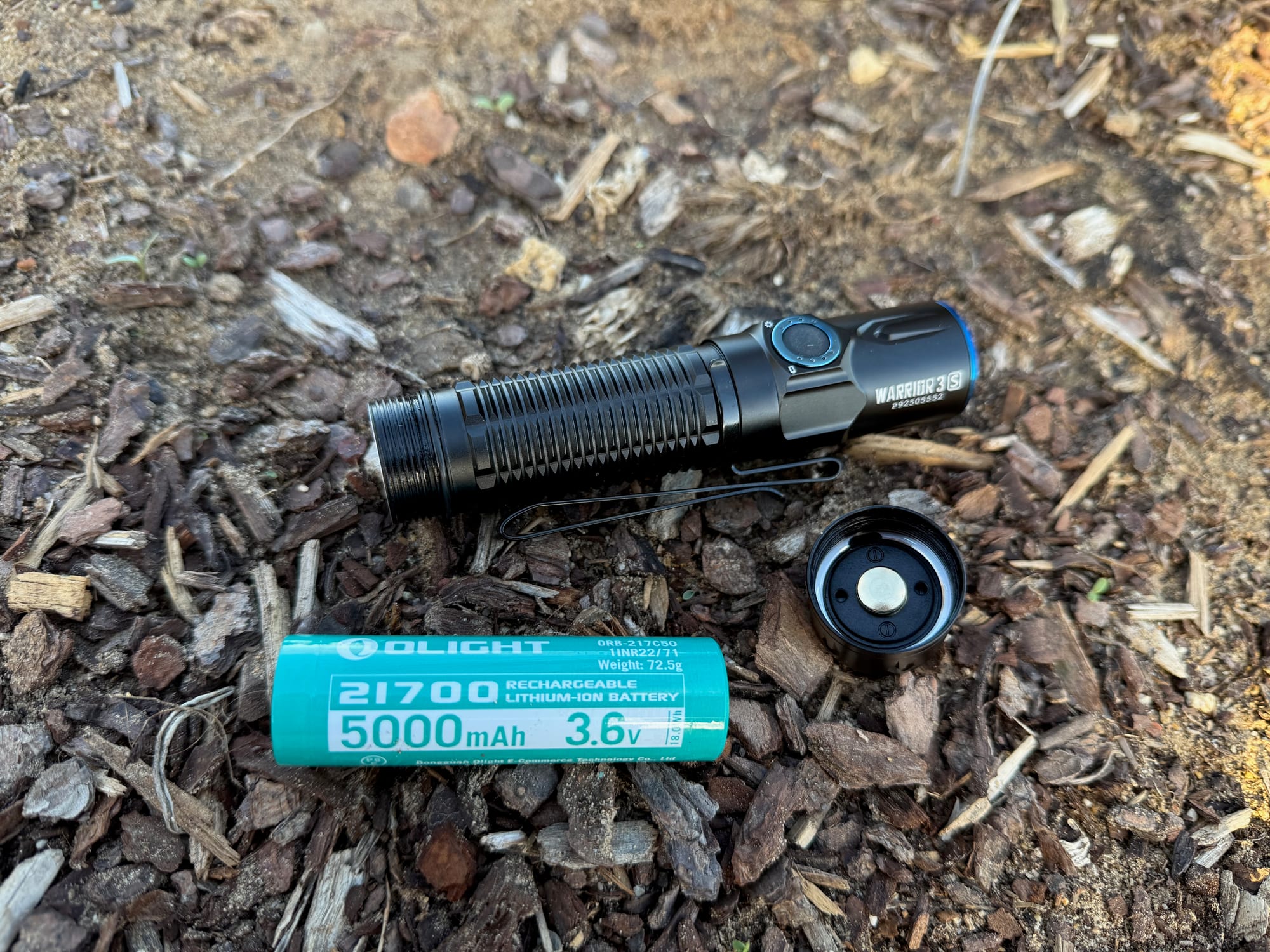 The Warrior 3S with its tail cap off and the Olight 21700 5,000 mAh battery beside it