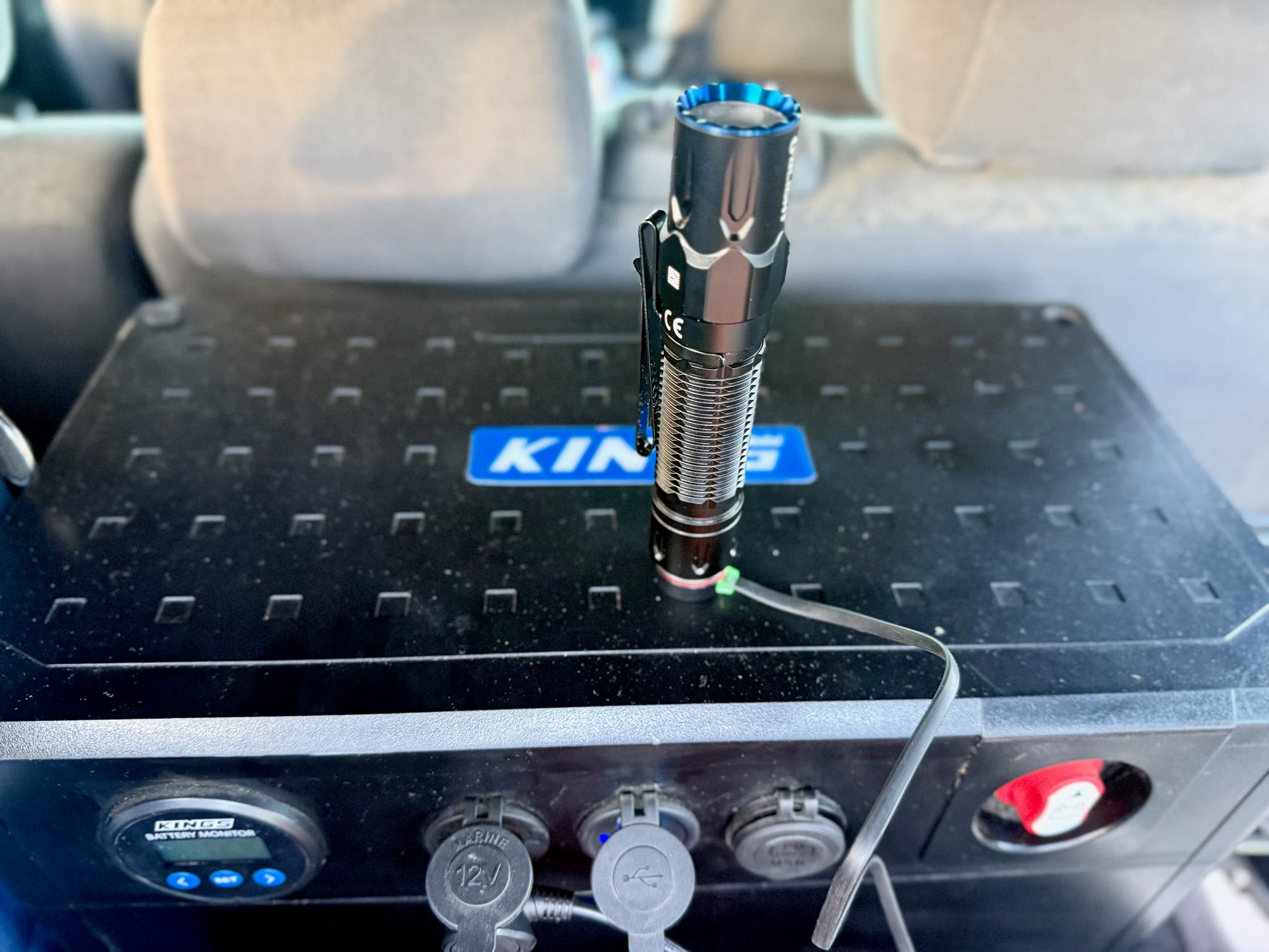 The Warrior 3S standing on its tail, charging on its magnetic cable on the 12V box in a 4WD