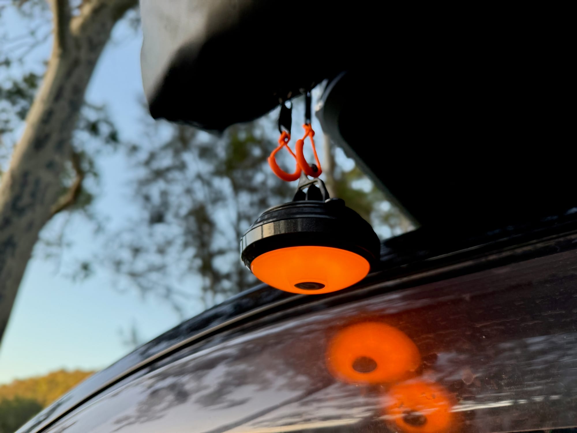 The OZtrail Portable Camp Light glowing amber under the rooftop tent