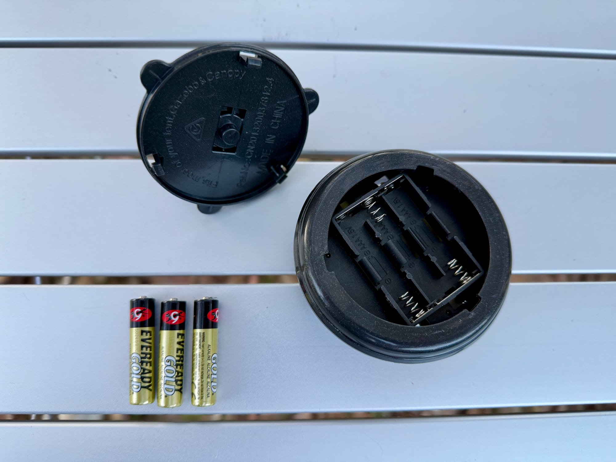 The battery compartment of the OZtrail Portable Camp Light with three AAA batteries
