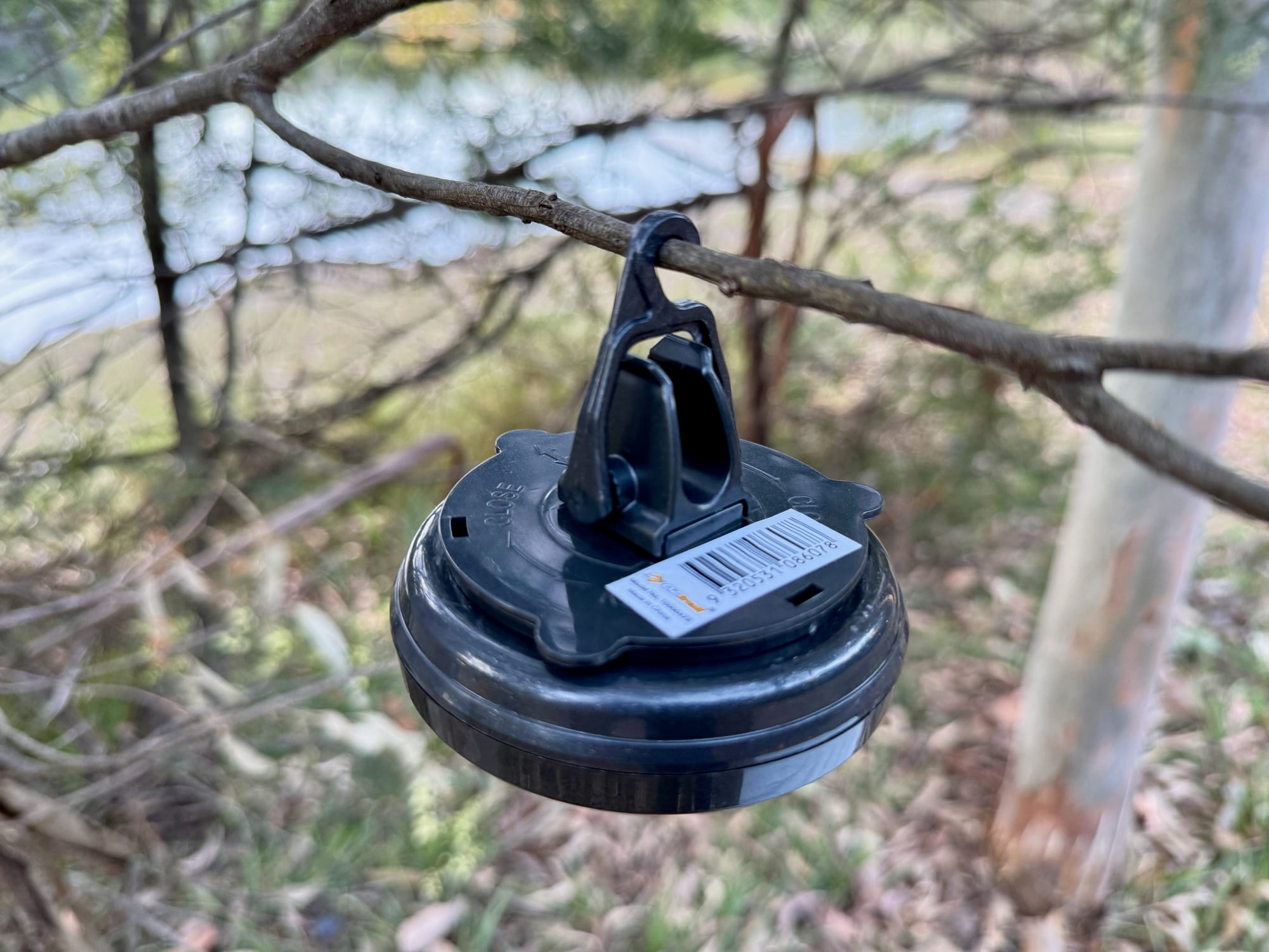 The hanger of the OZtrail Portable Camp Light hooked over a thin branch