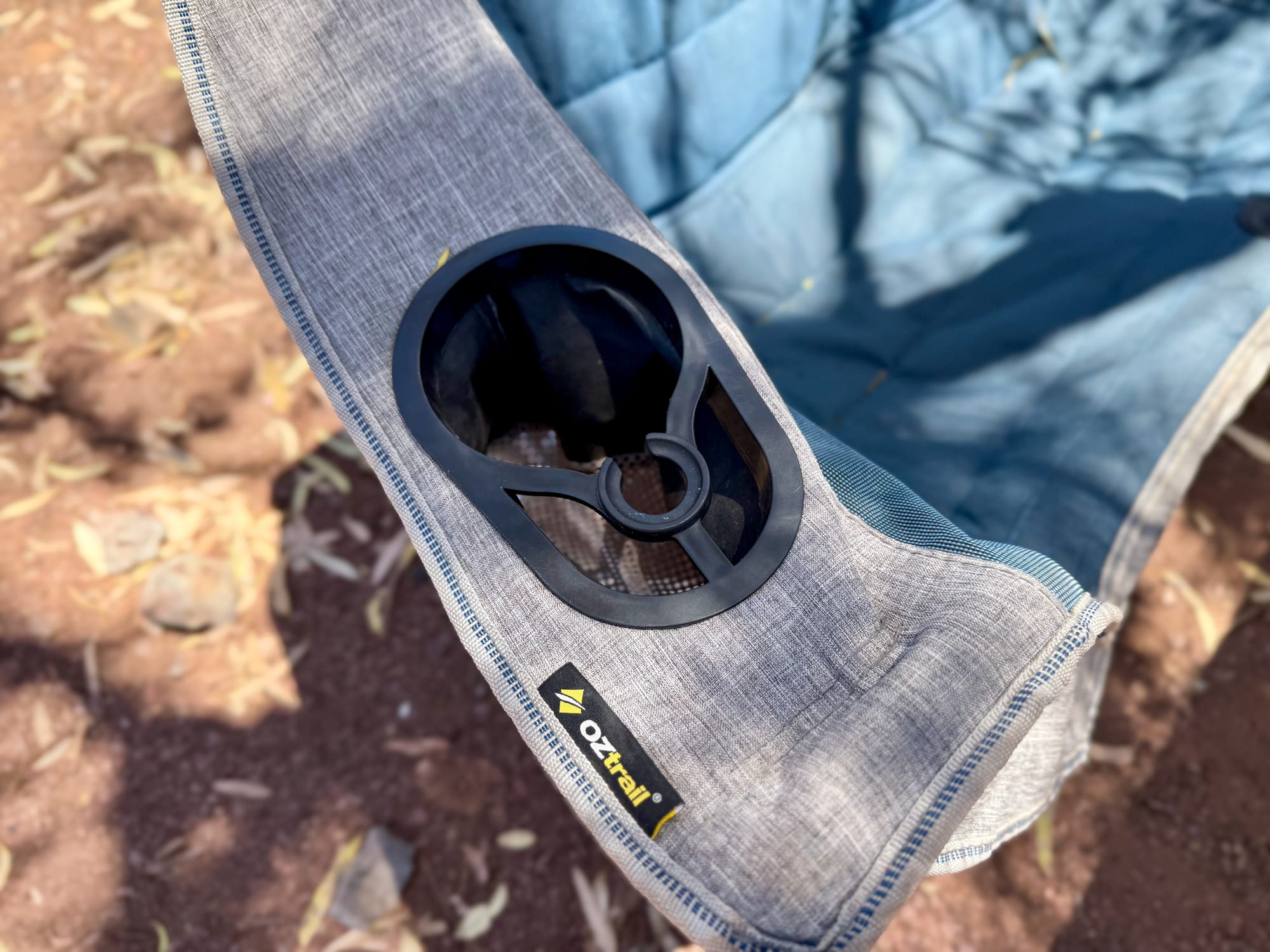 The cup holder in the padded arm of the OZtrail Galaxy 2 seater, with its keyhole slot and the OZtrail label