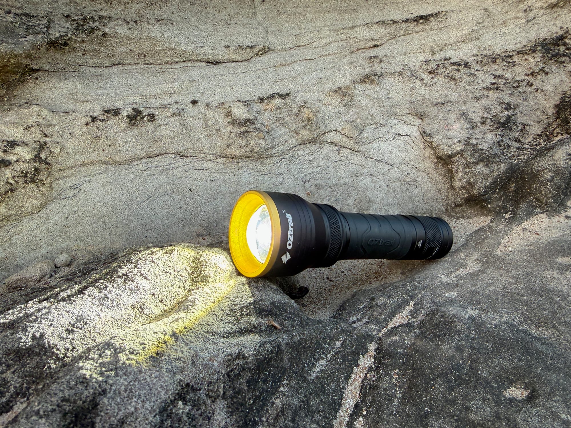 The F300 switched on, lying on a sandstone rock and lighting up the rock face