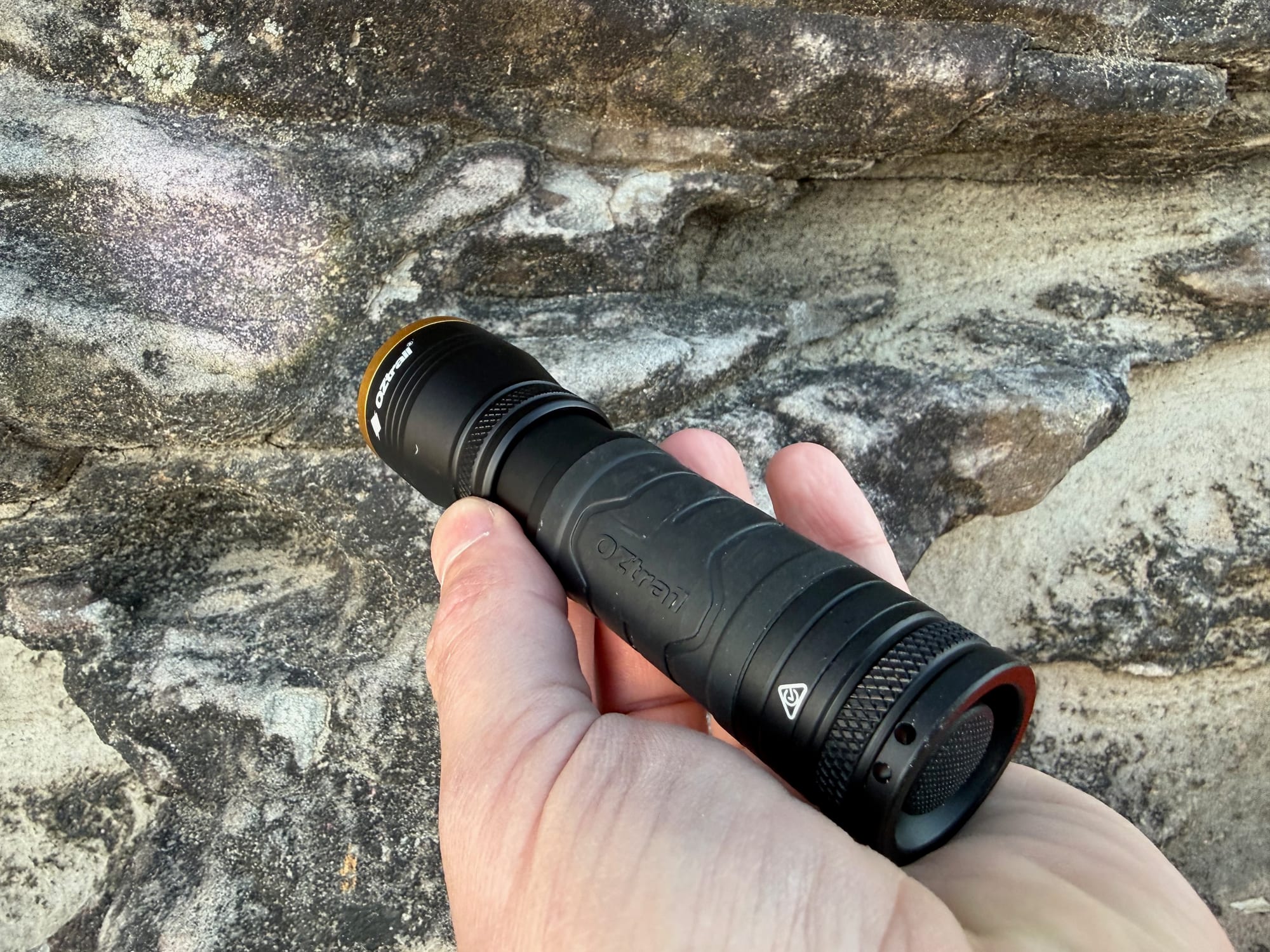 The OZtrail Lumos F300 held in a hand above a sandstone rock