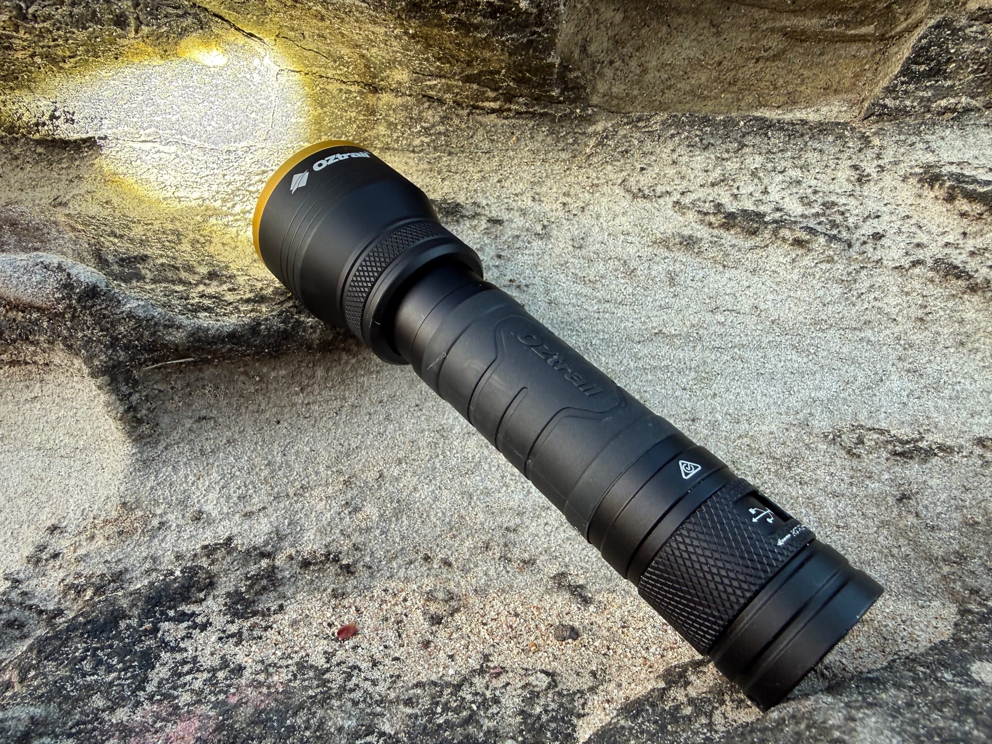 The FR800 switched on, lying on a sandstone rock and lighting up the rock face