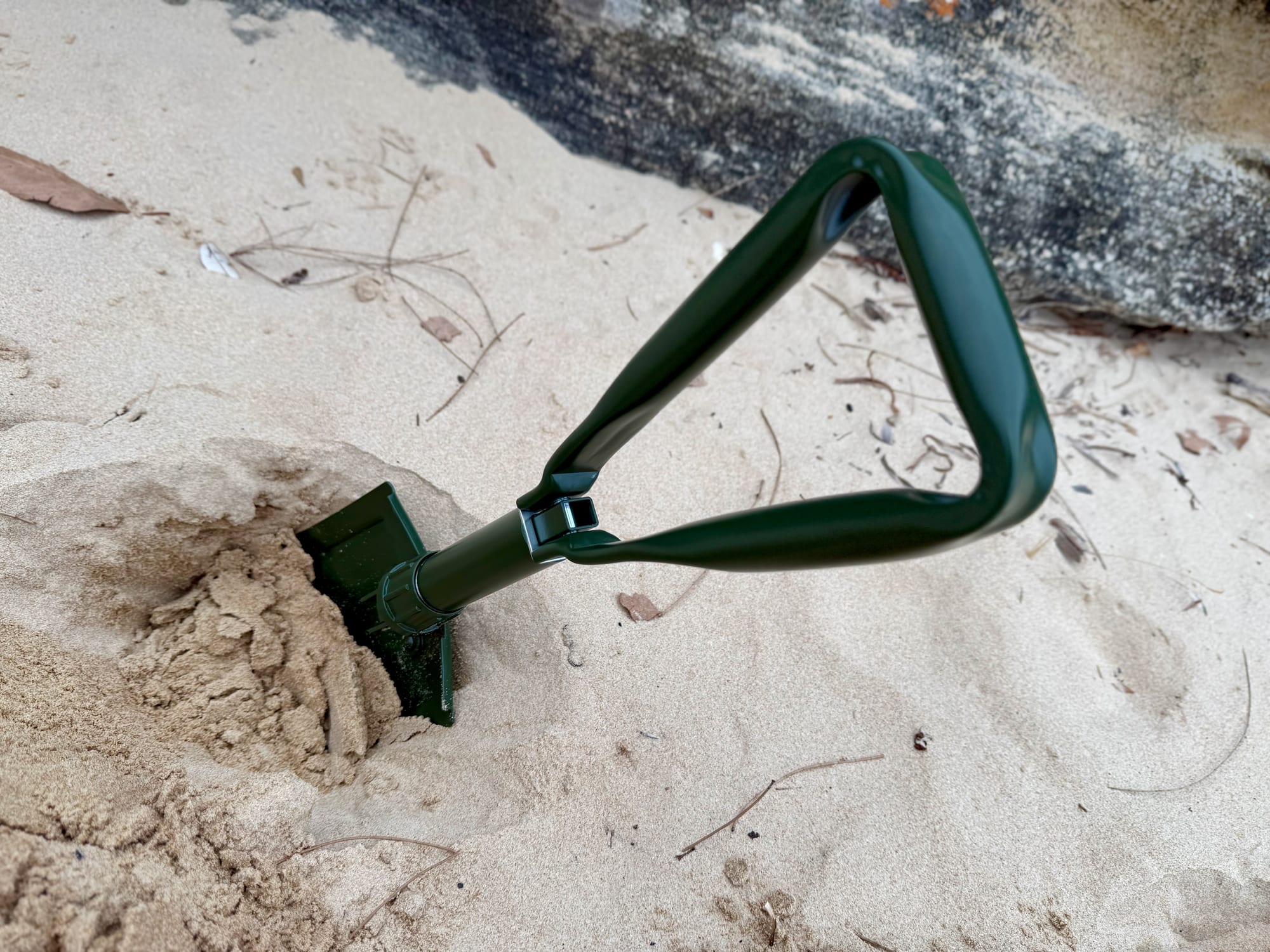 The OZtrail Tri-Fold Shovel digging a hole in beach sand