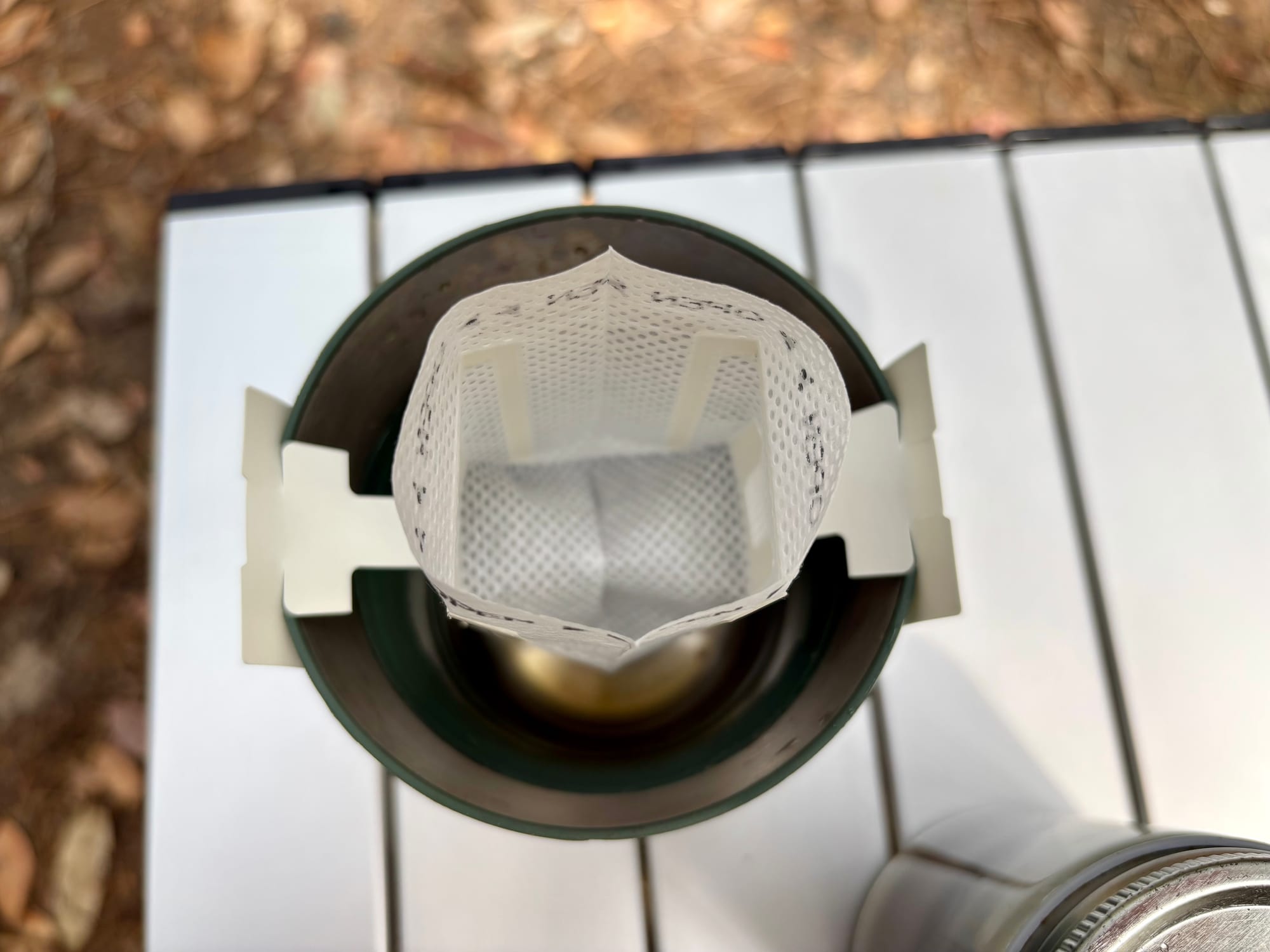 The opened filter bag hanging on the rim of a mug, seen from above