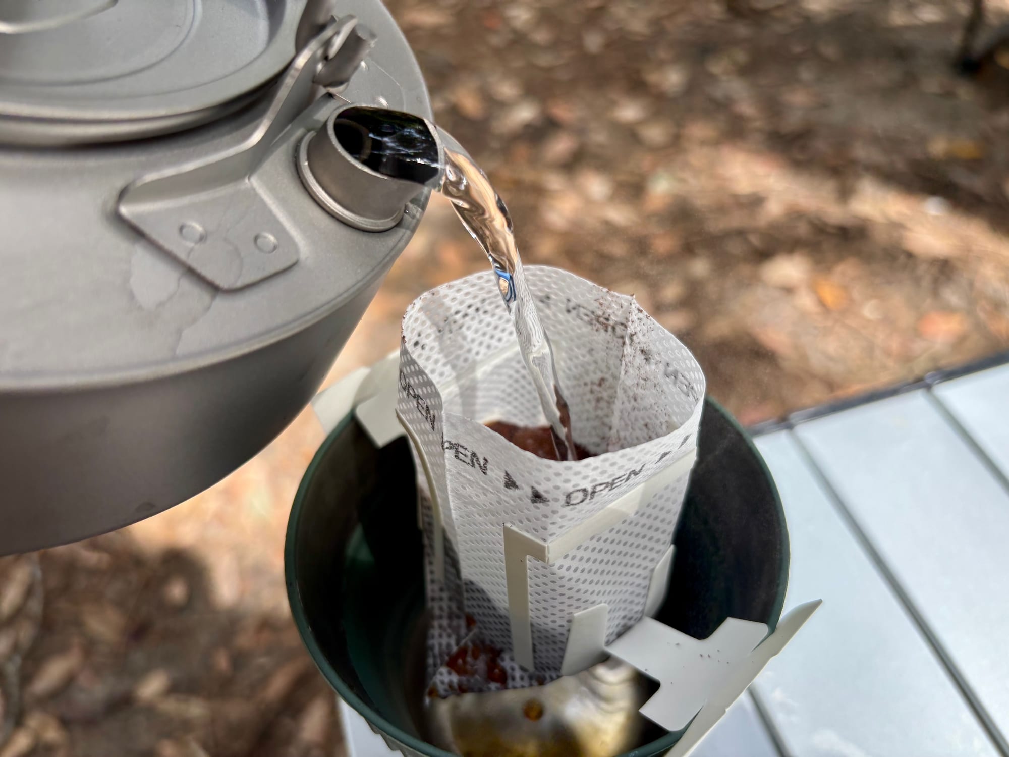 Pouring hot water from a kettle into the drip coffee filter bag