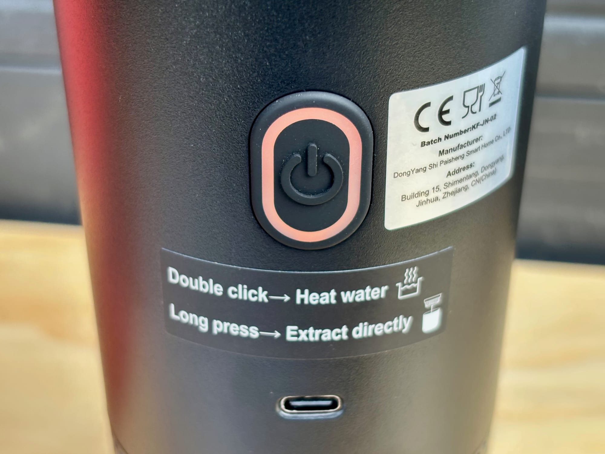 The power button, the instruction sticker and the USB-C port on the portable espresso machine