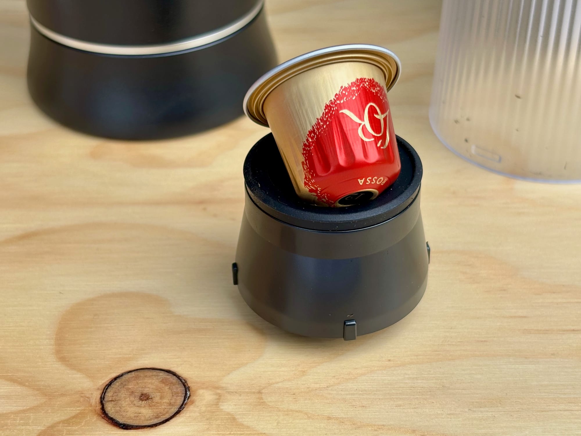 A red and gold coffee capsule sitting in the capsule holder of the portable espresso machine