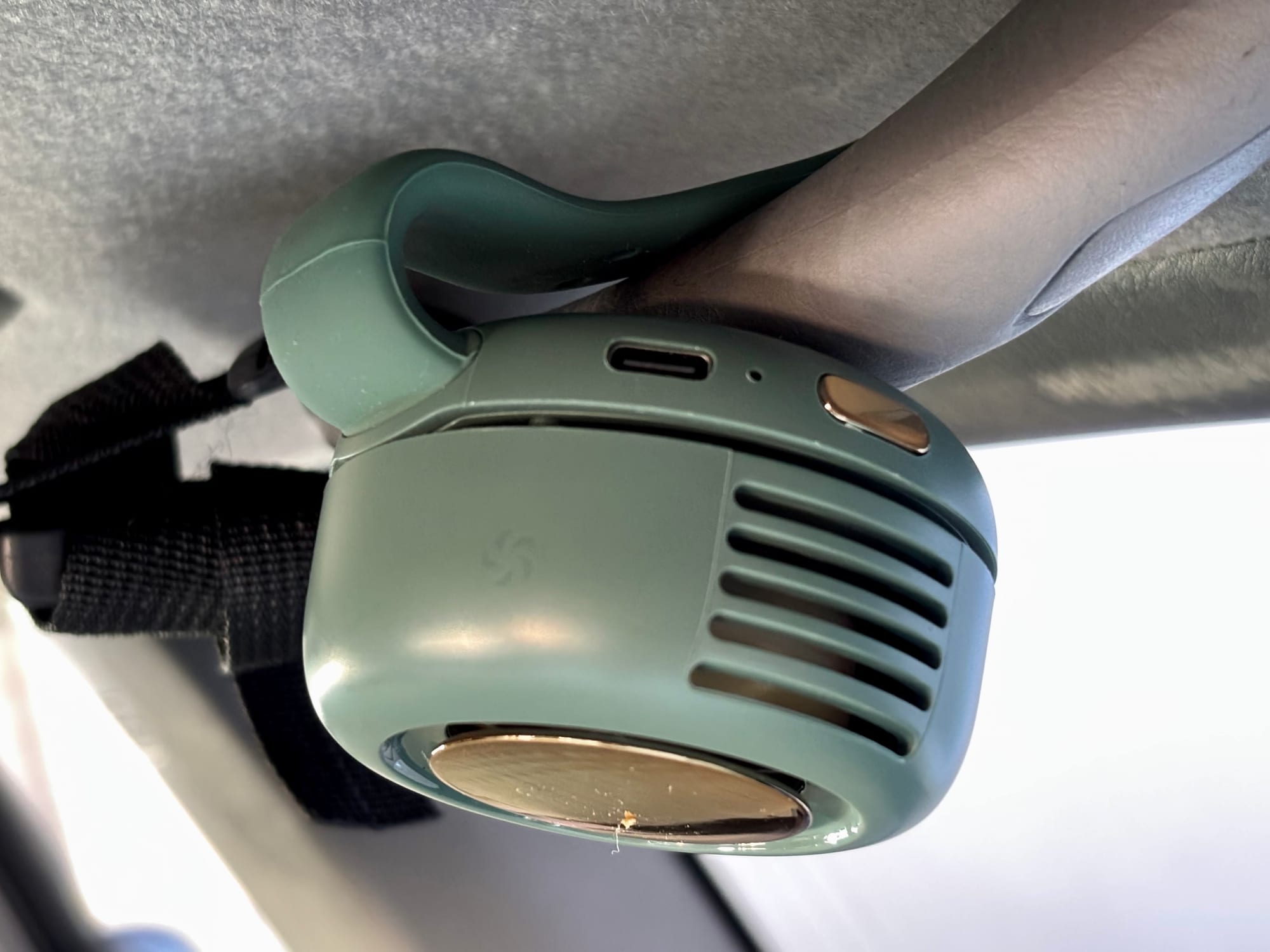 The mini bladeless fan clipped onto the grab handle above a car door
