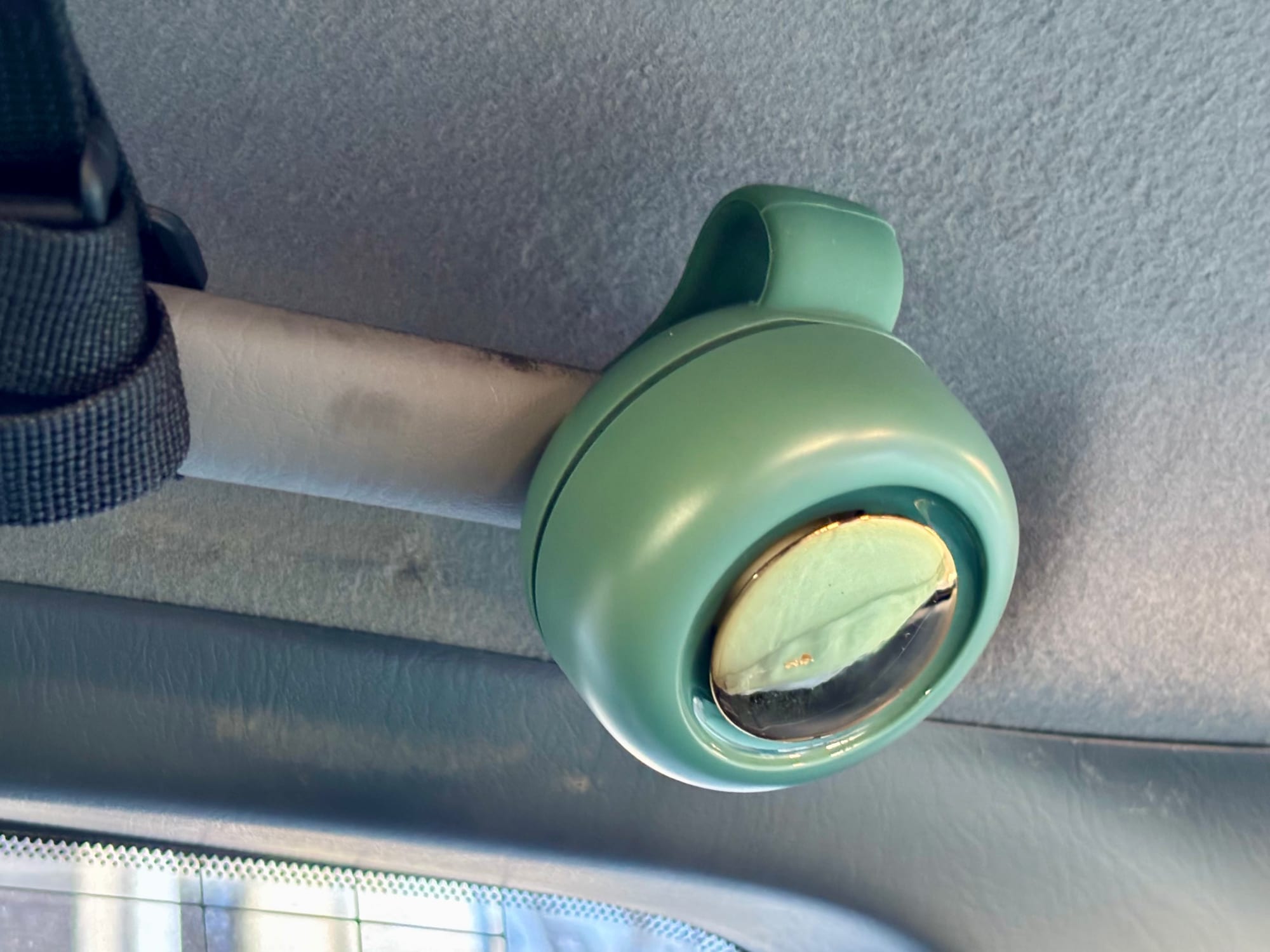 The mini bladeless fan seen from the front, clipped to a grab handle in the car