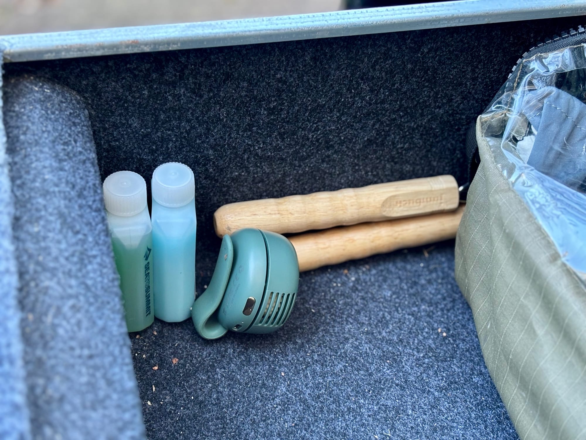 The mini bladeless fan lying in a drawer next to small travel bottles