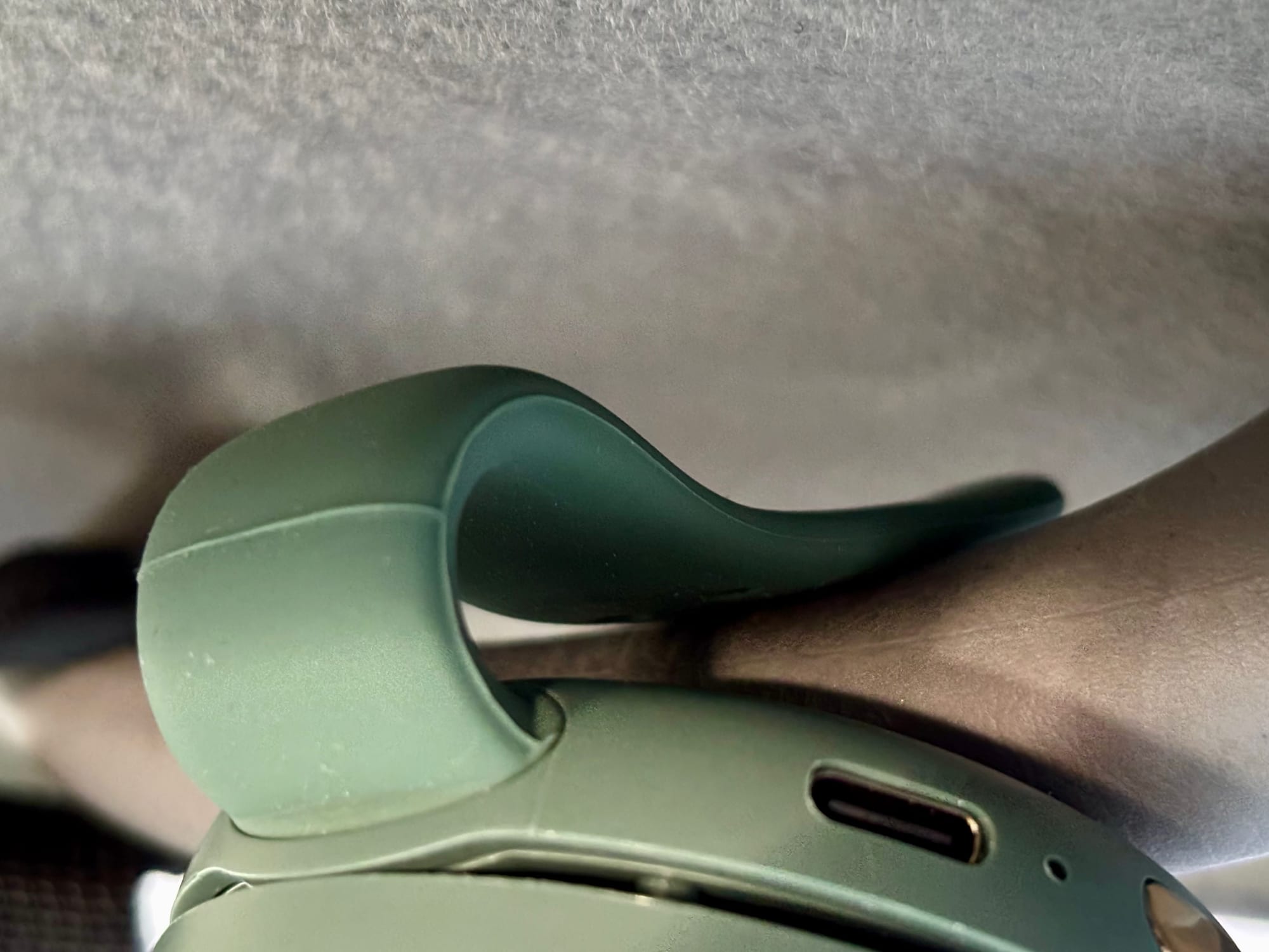 The silicone clip arm of the mini fan gripping a grab handle
