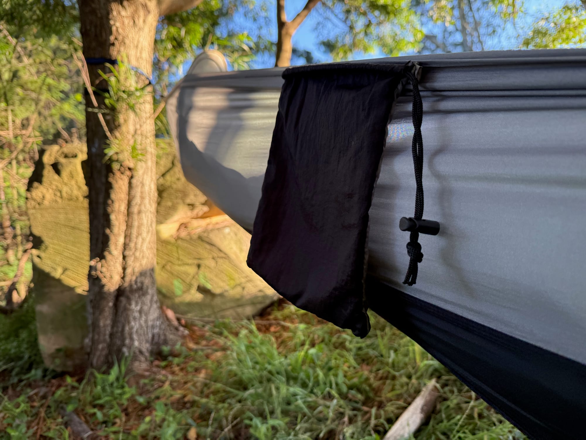 The black stuff sack hanging from the side of the hammock as a pocket